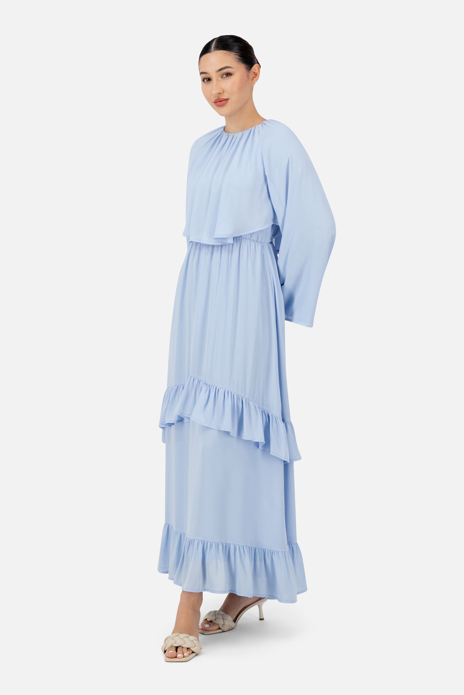 Girl posing in the powder blue FARES long sleeve maxi dress with soft ruffle trims and an elegant flowing silhouette.