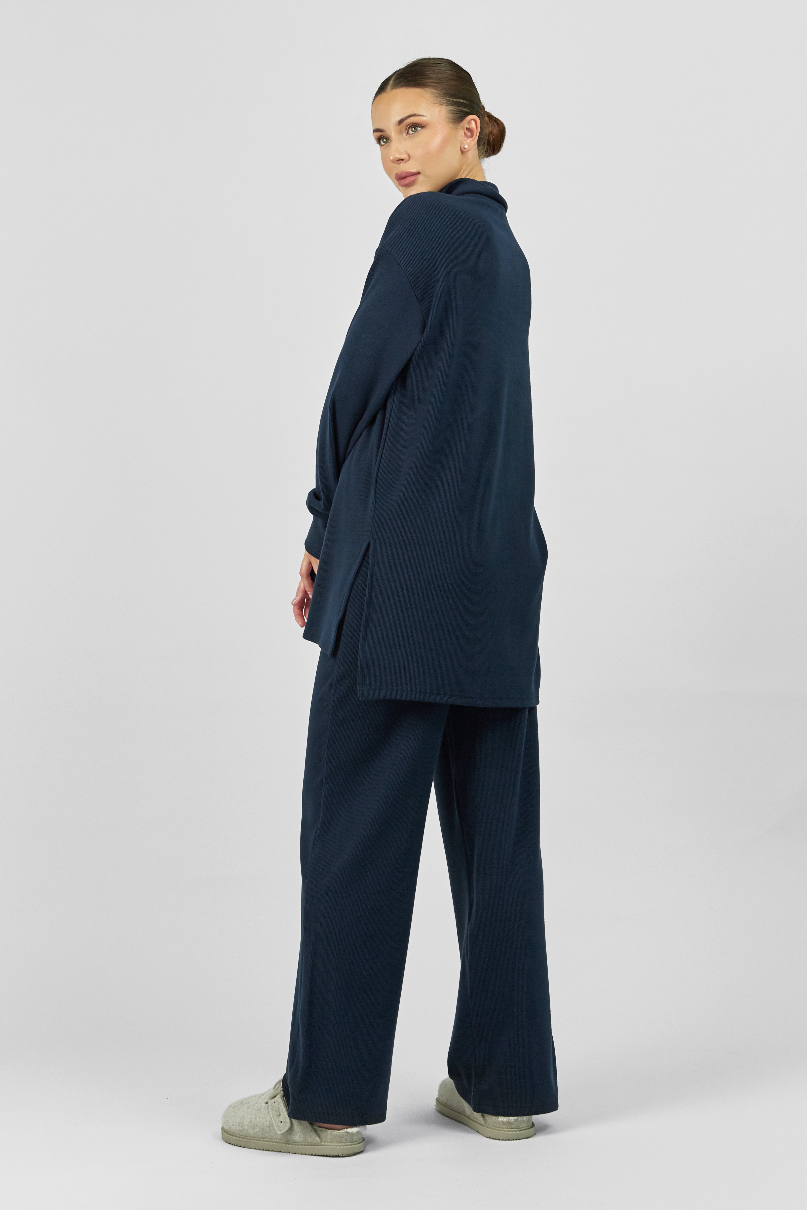A girl wearing FARES' velour knit half zip is shown from the back while looking over her left shoulder. Colour description: Navy Blue.