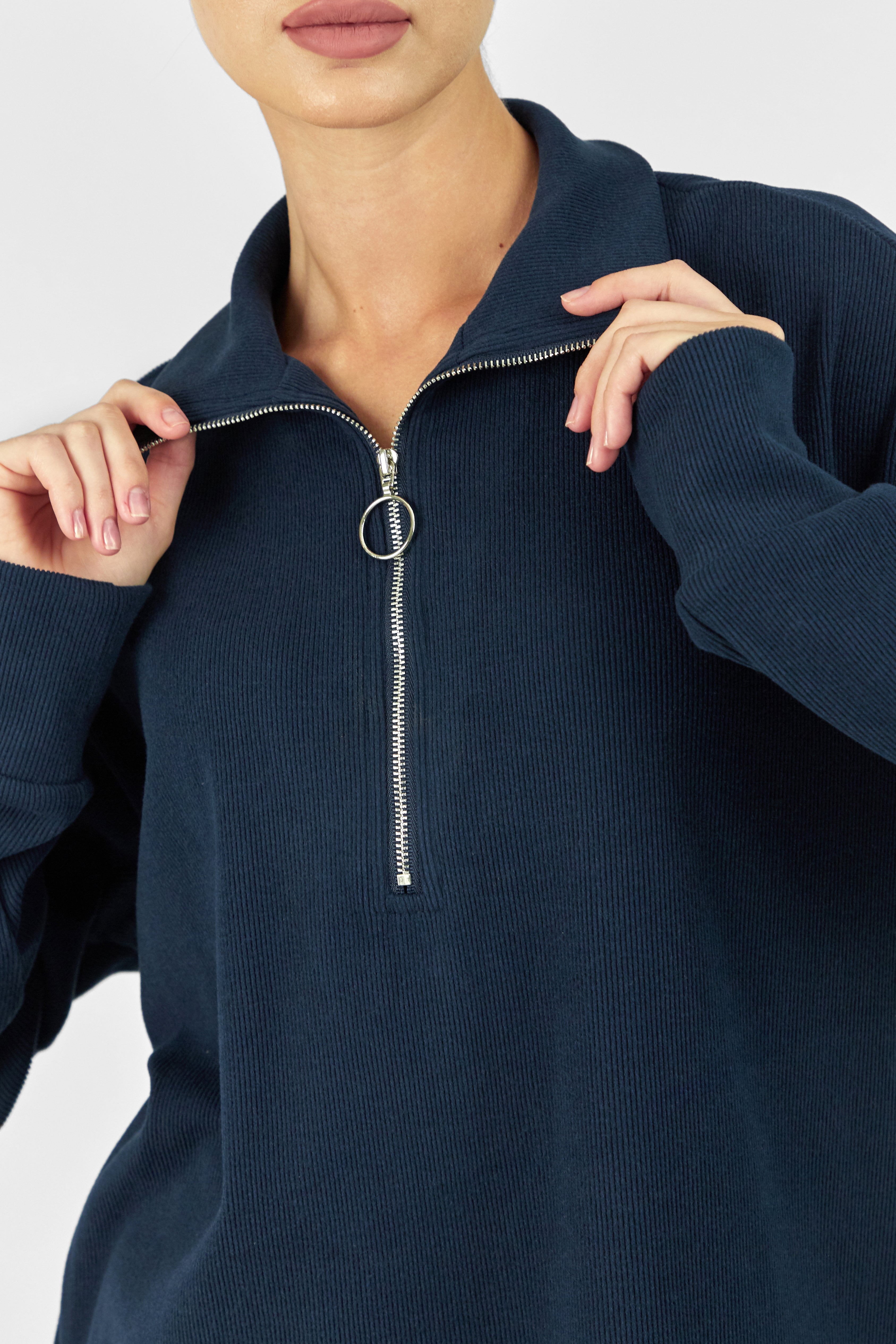 A close up of the model showing the zip of FARES' velour knit half zip. Colour description: Navy Blue.