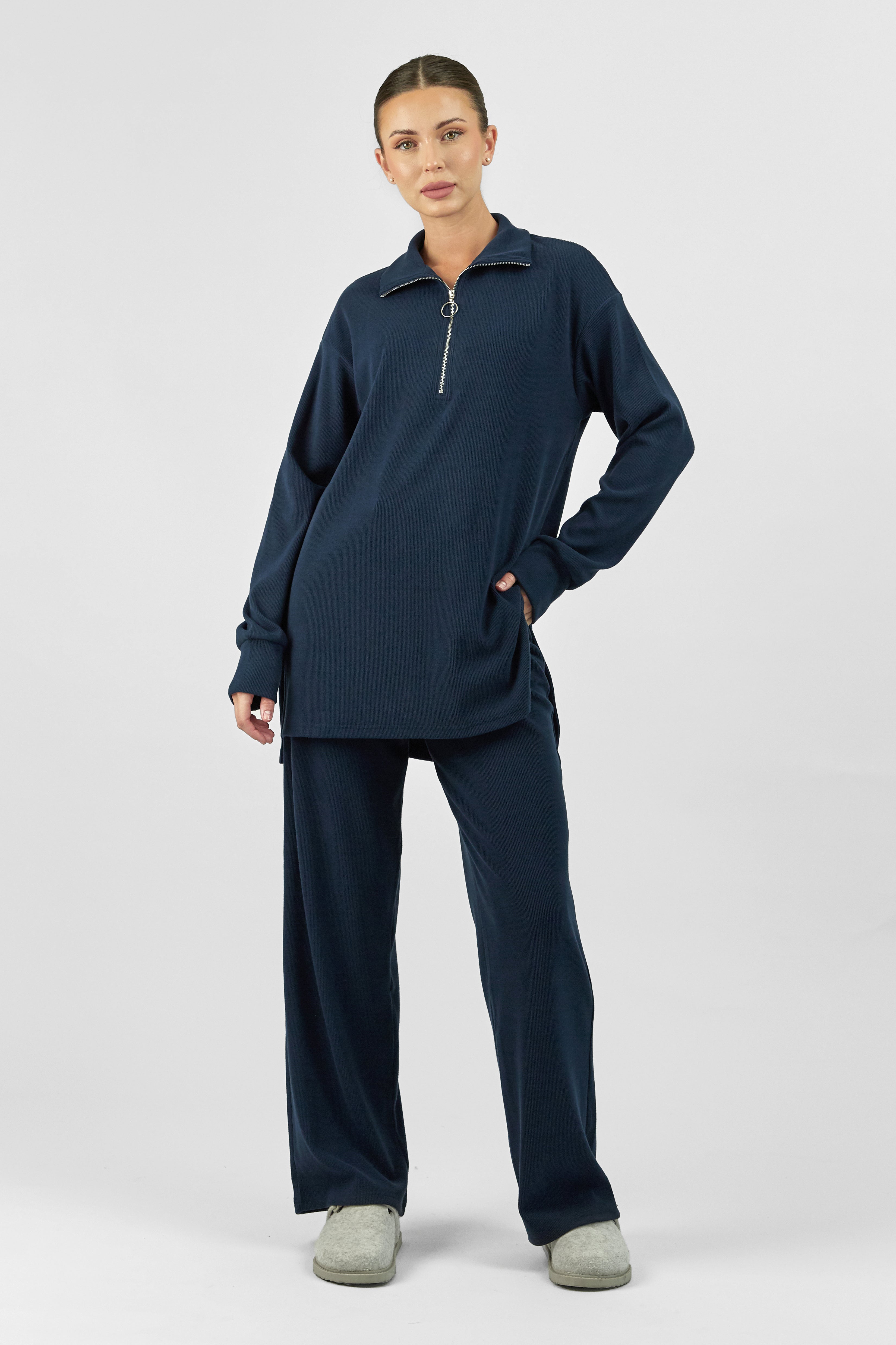 A model is wearing FARES' velour knit half zip. She is standing with her left hand in her pocket. Colour description: Navy Blue.