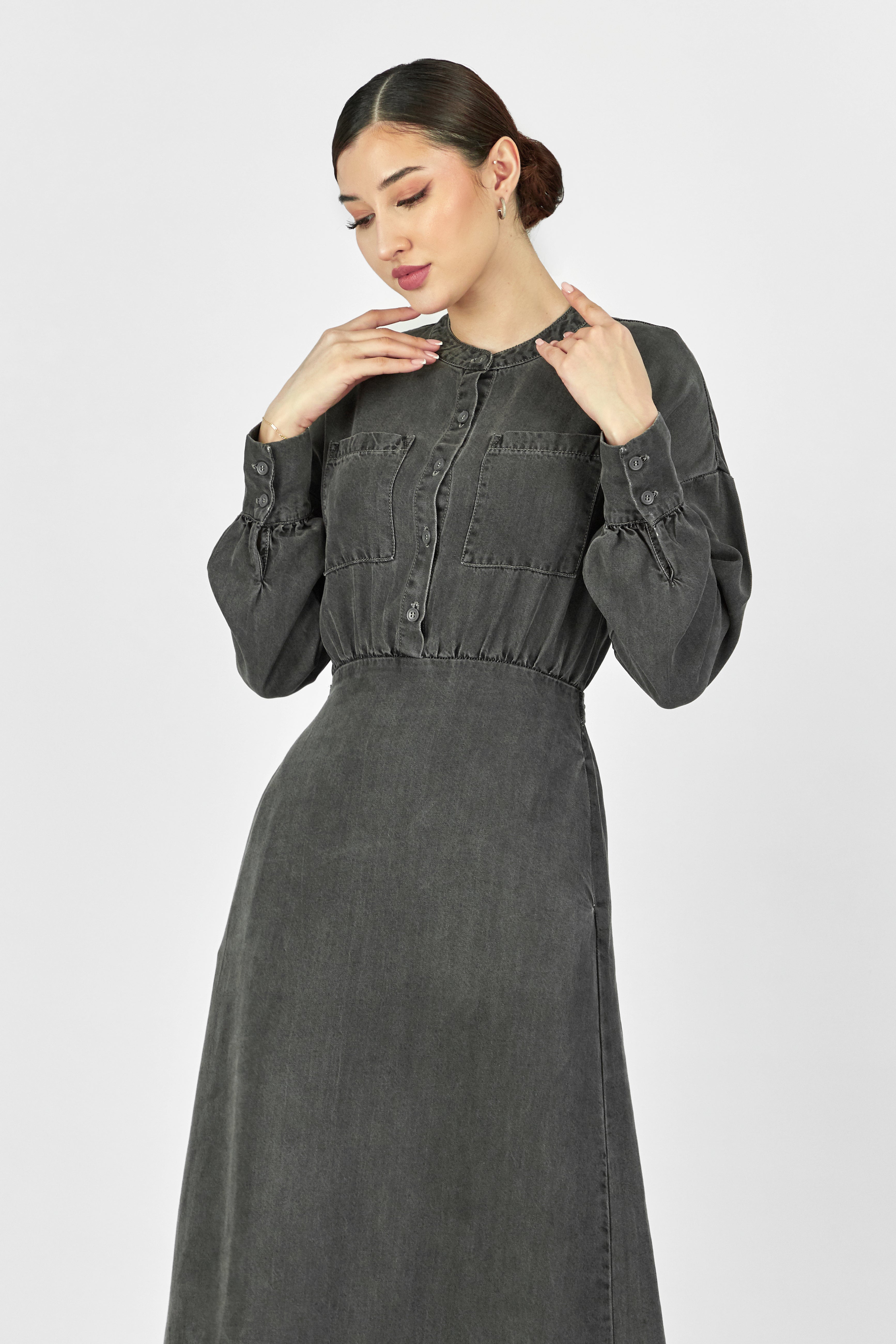 A model is wearing FARES' soft touch denim style dress while touching her neck. Colour description: Dark Grey.