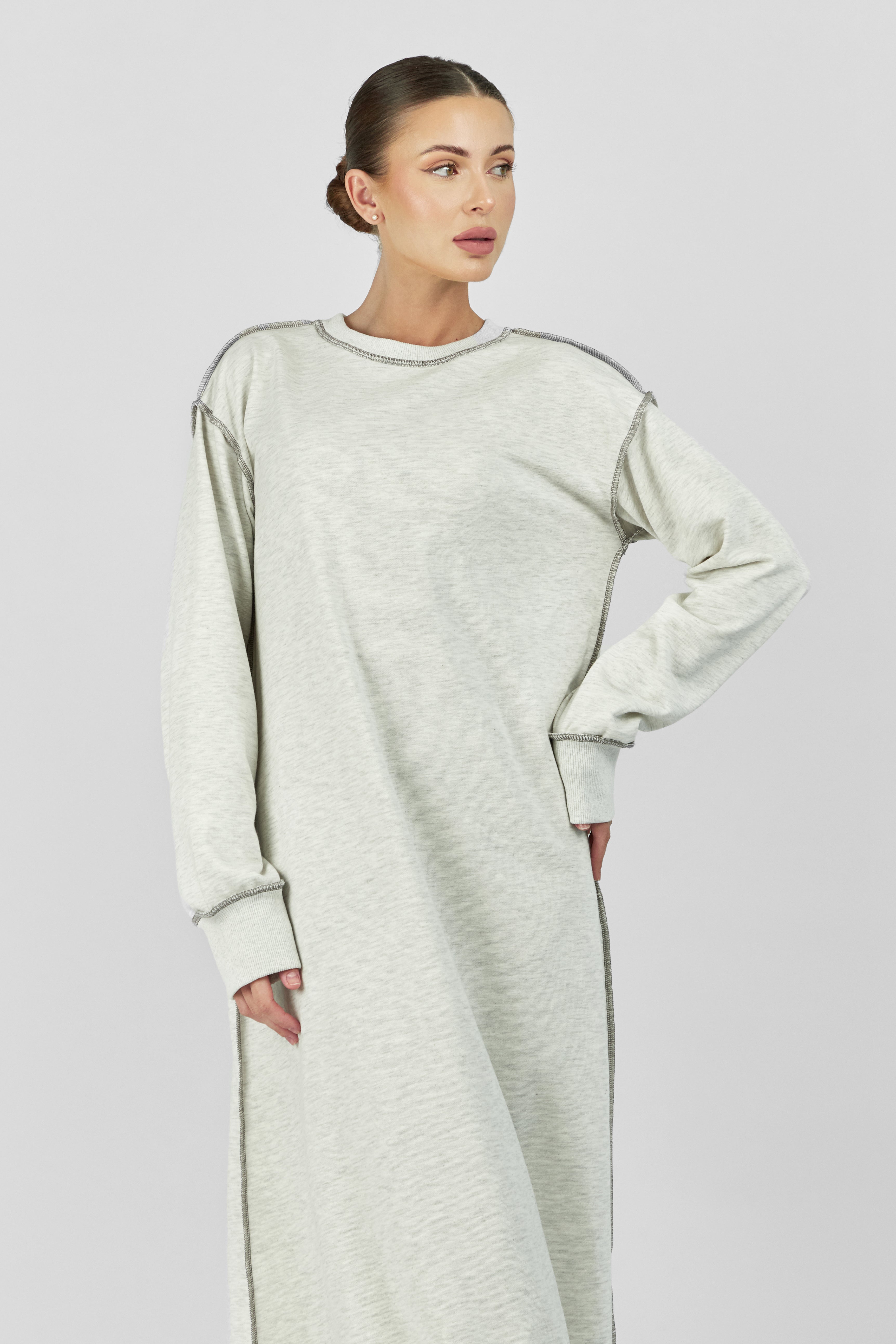 Colour: Warm Grey. A model with her hand on her vaist standing in a contrast stich dress.