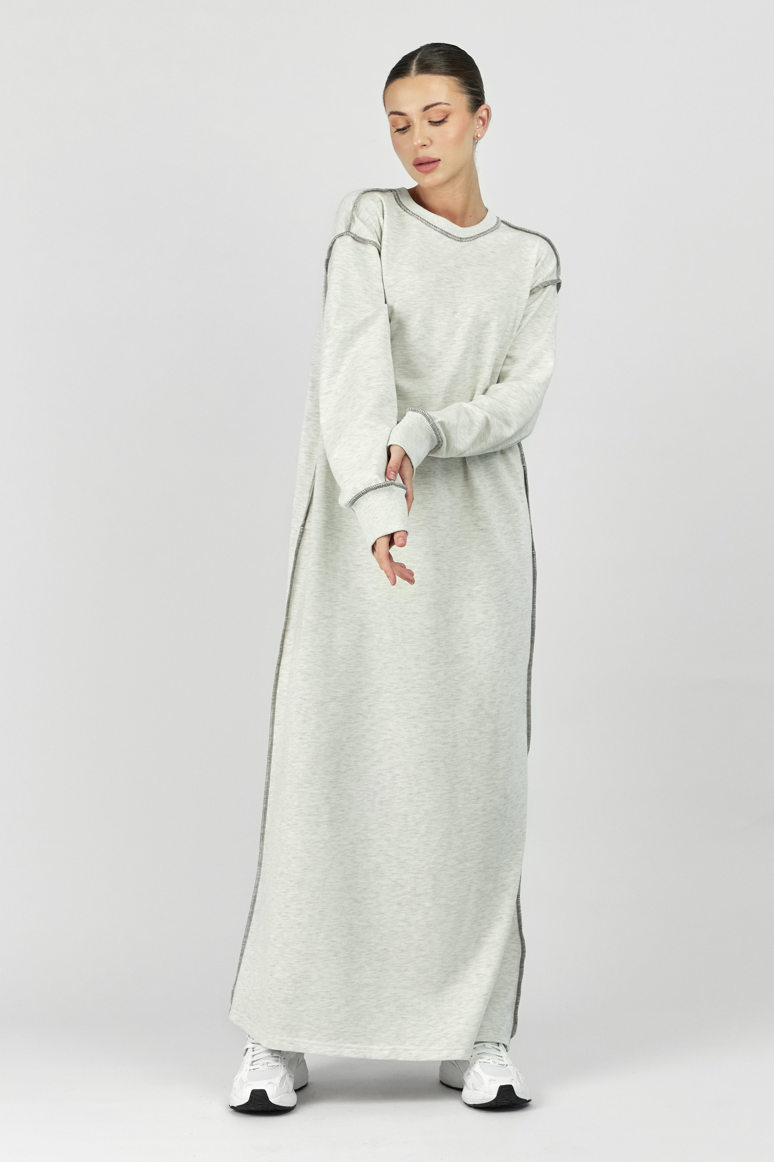 Colour: Warm Grey. A front pose of a model with her hands crossed in a contrast stich dress.