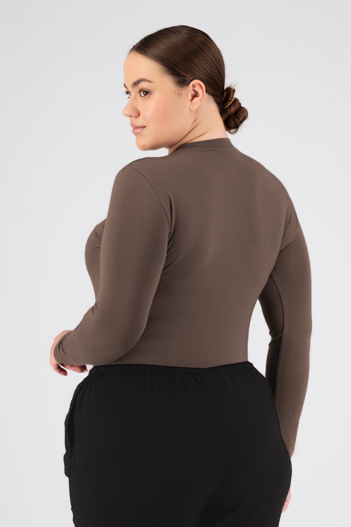 The model wearing FARES' long sleeve layer is shown from the back while looking over her left shoulder. Colour description: Cold Brown.