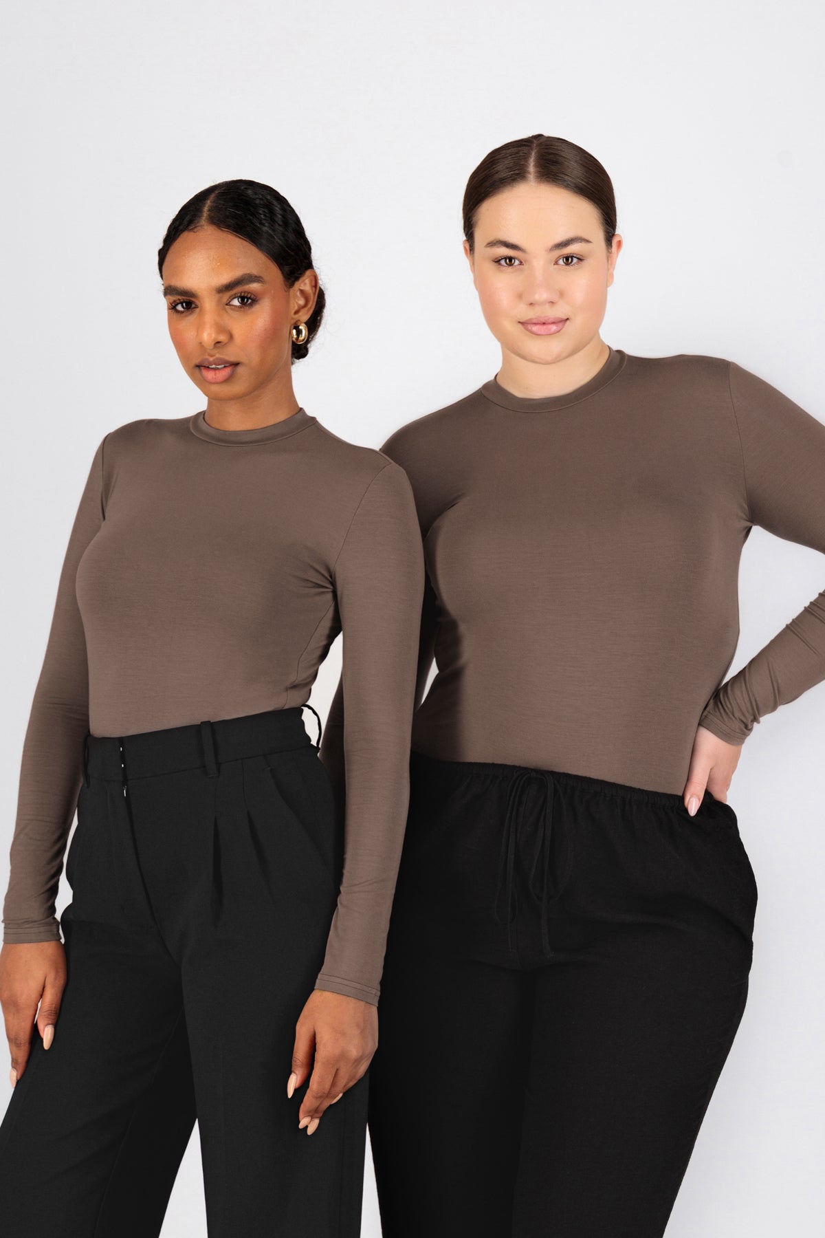 Two girls are standing side by side in a pose in FARES' best base layer clothing. Colour description: Cold Brown.