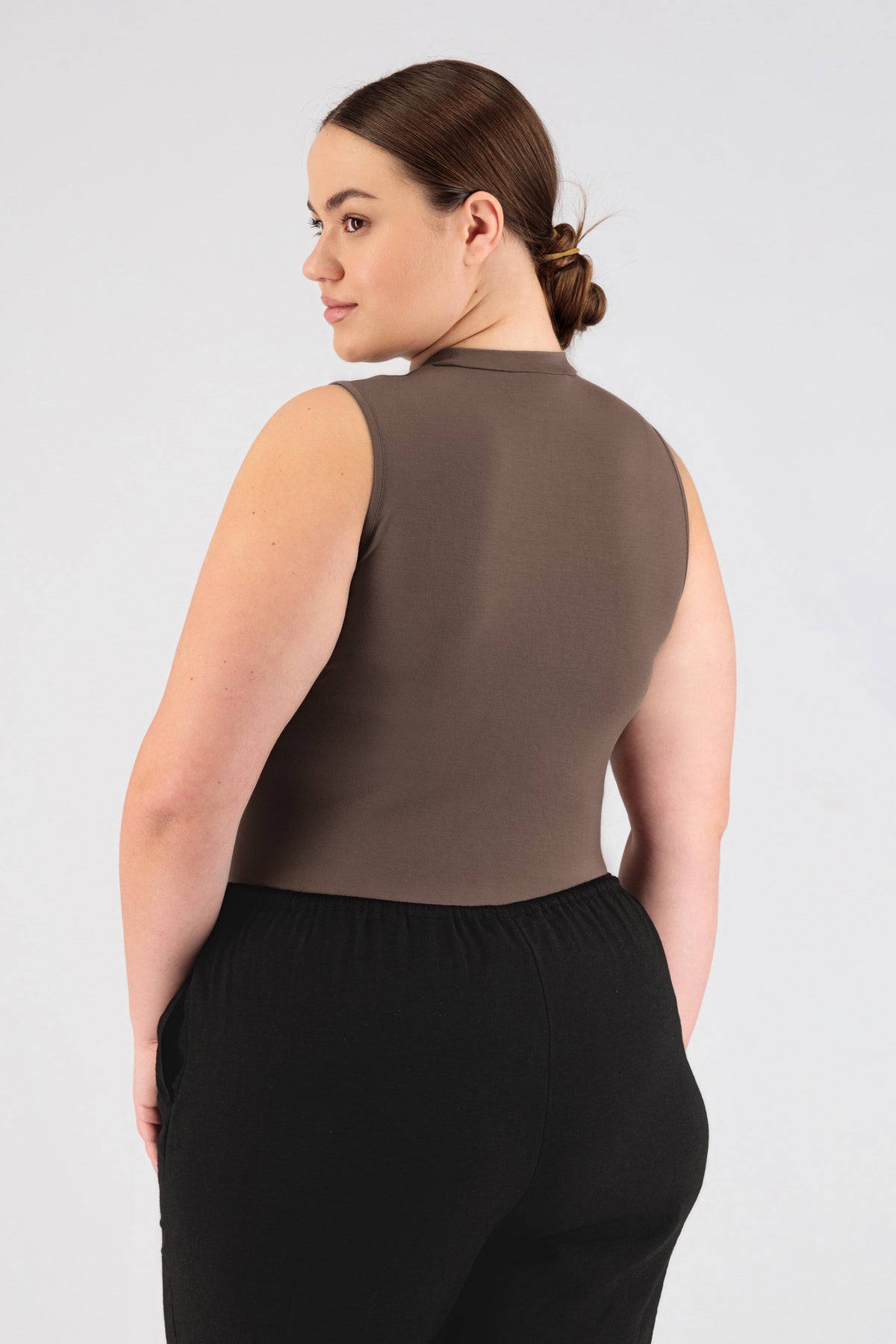 The model wearing FARES' sleeveless layer is shown from the back while looking over her left shoulder. Colour description: Ash Brown.
