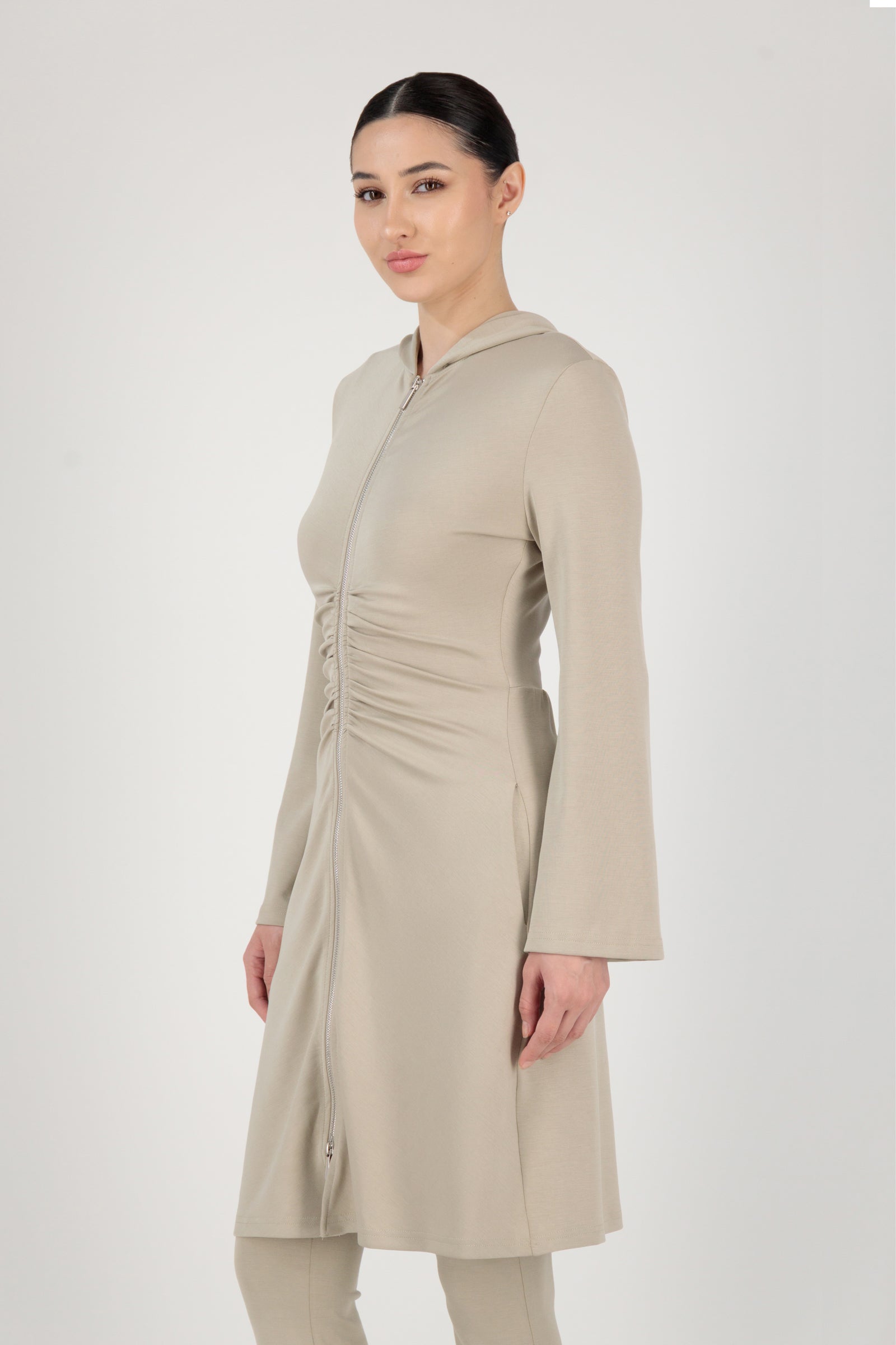 Side angle of the FARES Buttery Gathered Waist Long Hoodie in Stone presenting a refined essential hoodie shape with gentle structure.