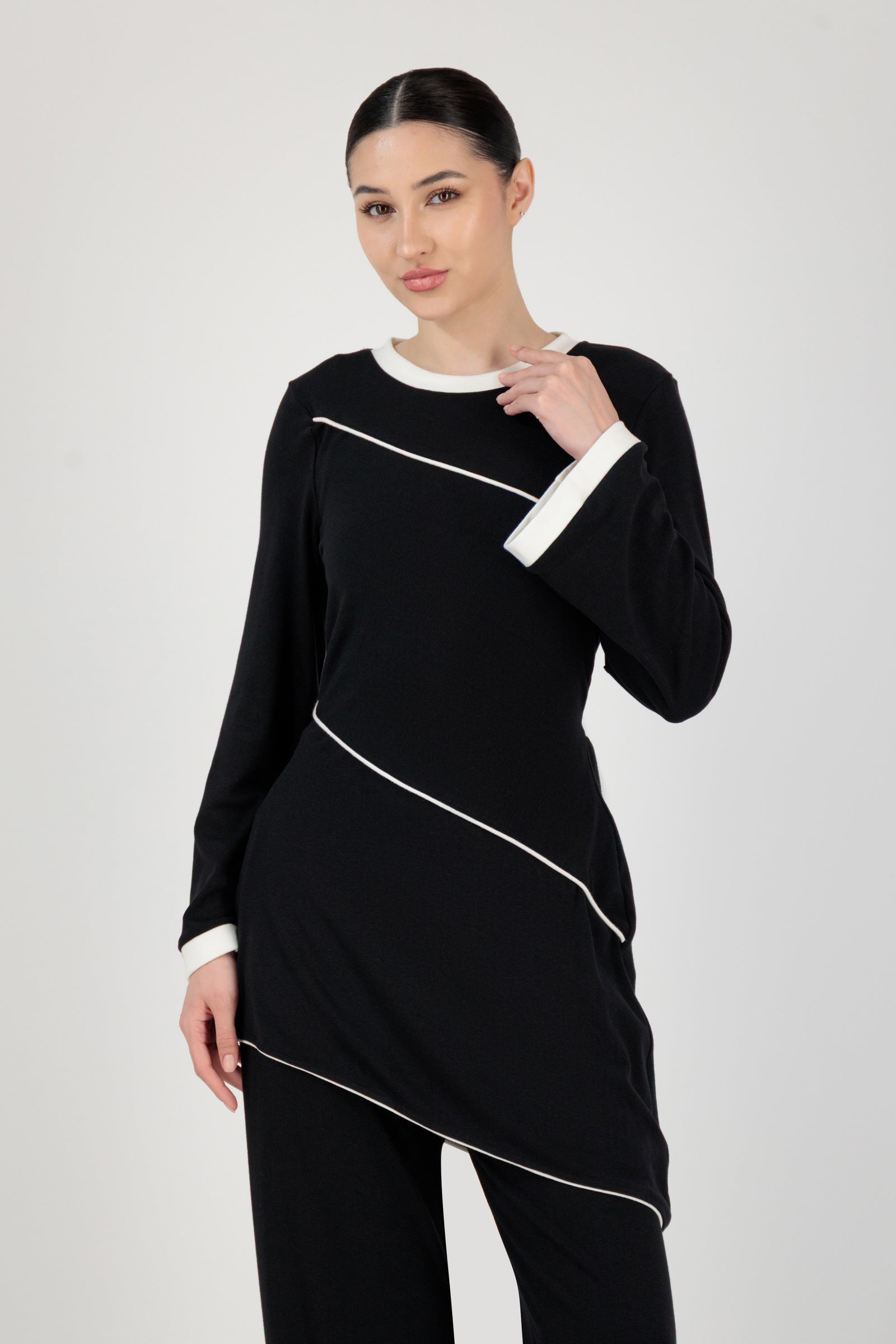The FARES Slanted Contrast Detail Knit Tunic in Black styled naturally, showing how this tunic balances structure with ease through its design lines.