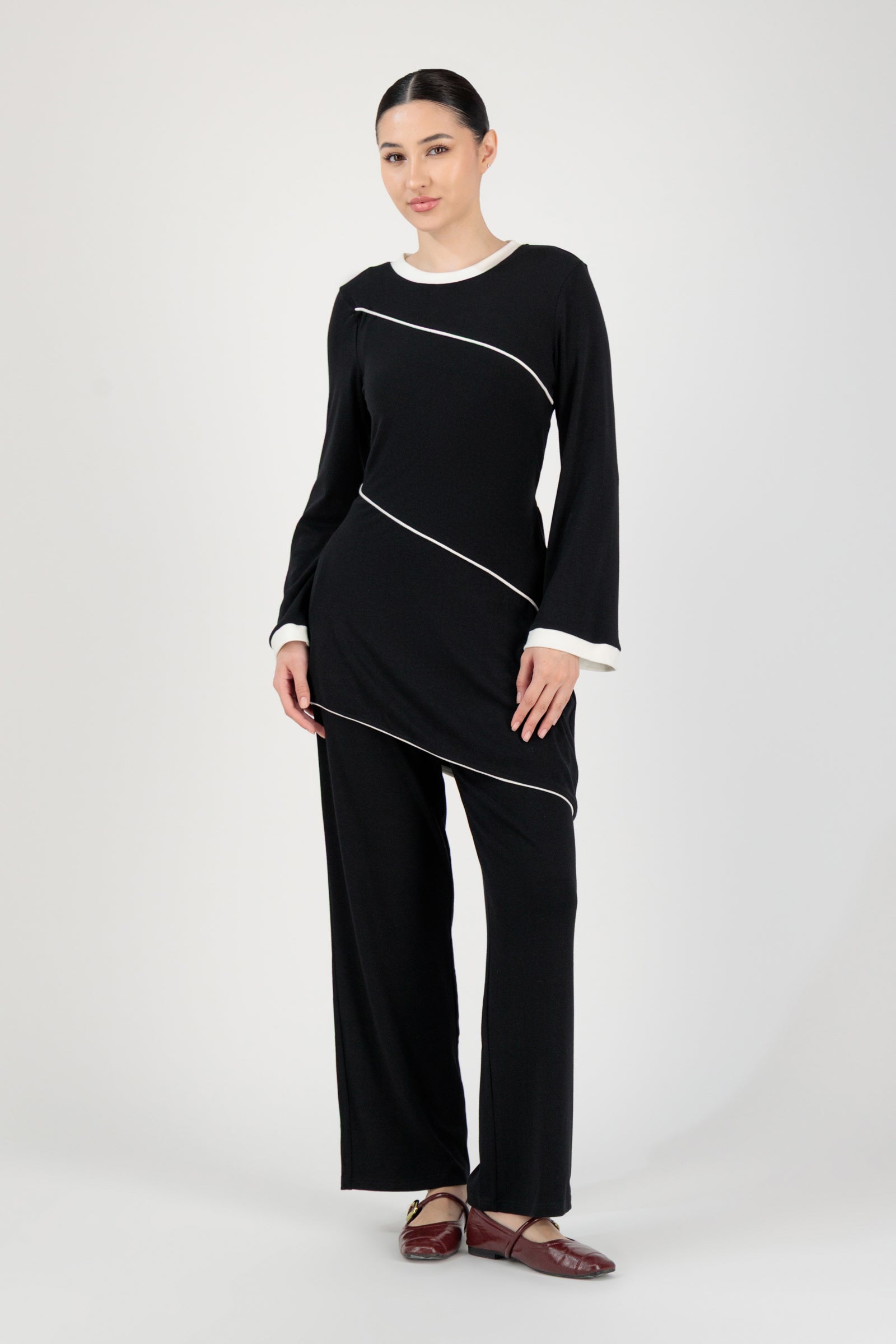 Full-length view of the FARES Slanted Contrast Detail Knit Tunic in Black worn with matching trousers, creating a cohesive and polished tunic look.