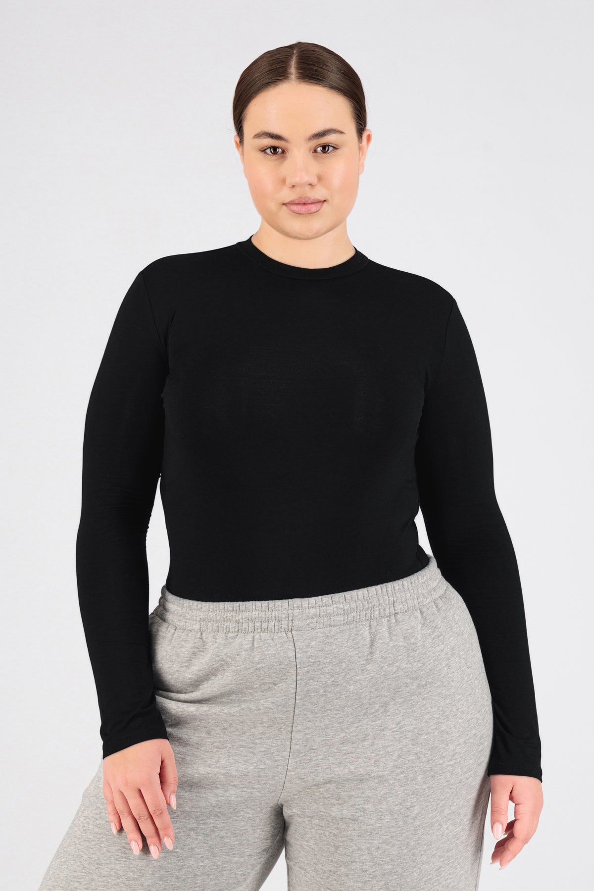 The model is wearing FARES' long sleeve layer. Colour description: Black. She is facing the camera in a base layer with perfect fit sleeves.