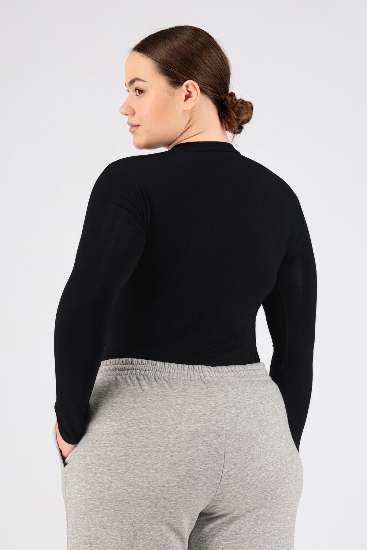 The girl wearing FARES' long sleeve layer is shown from the back while looking over her left shoulder. Colour description: Black.
