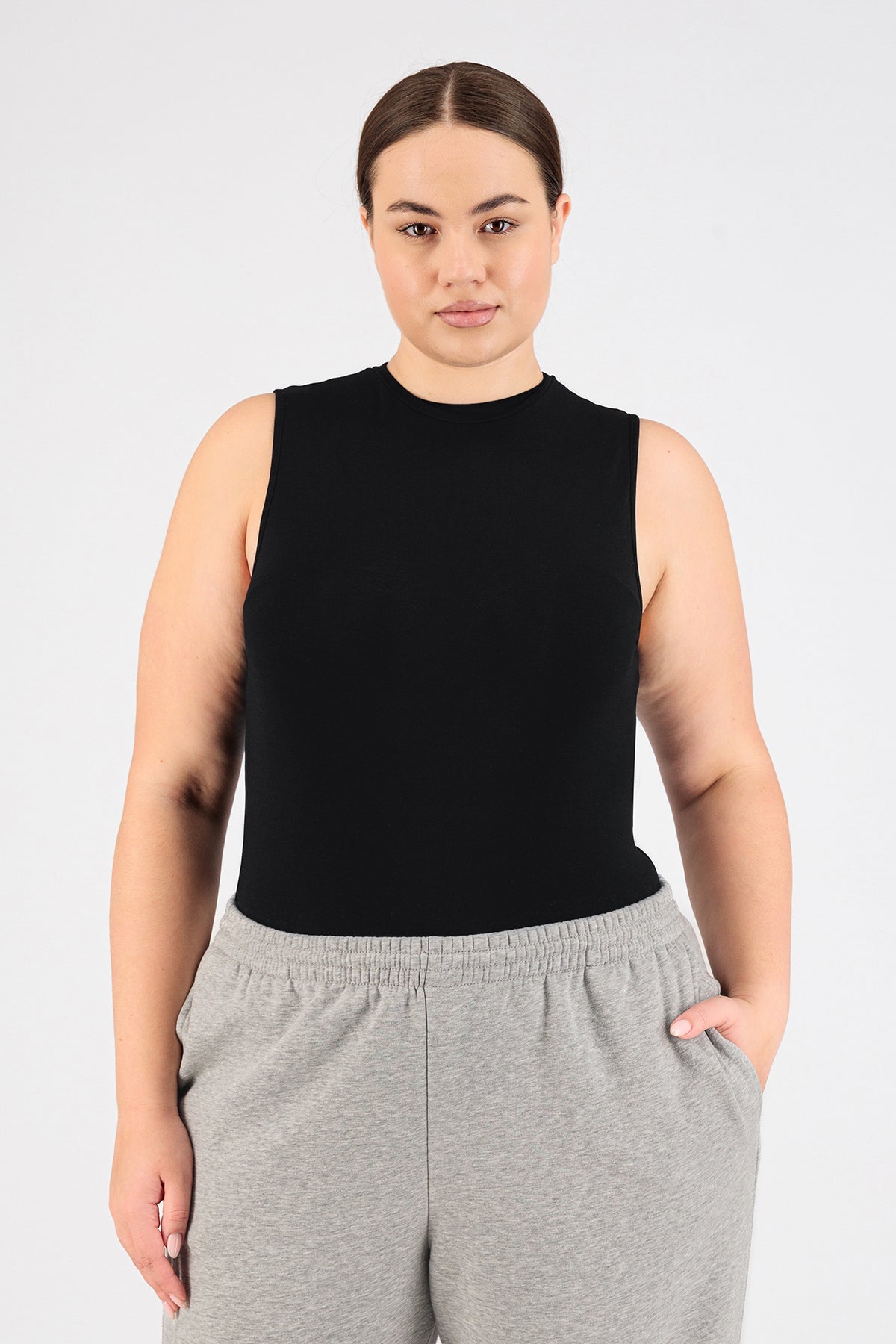 A girl is wearing FARES' sleeveless layer. Colour description: black. She is standing in the sleevless top with her left hand in her pocket.