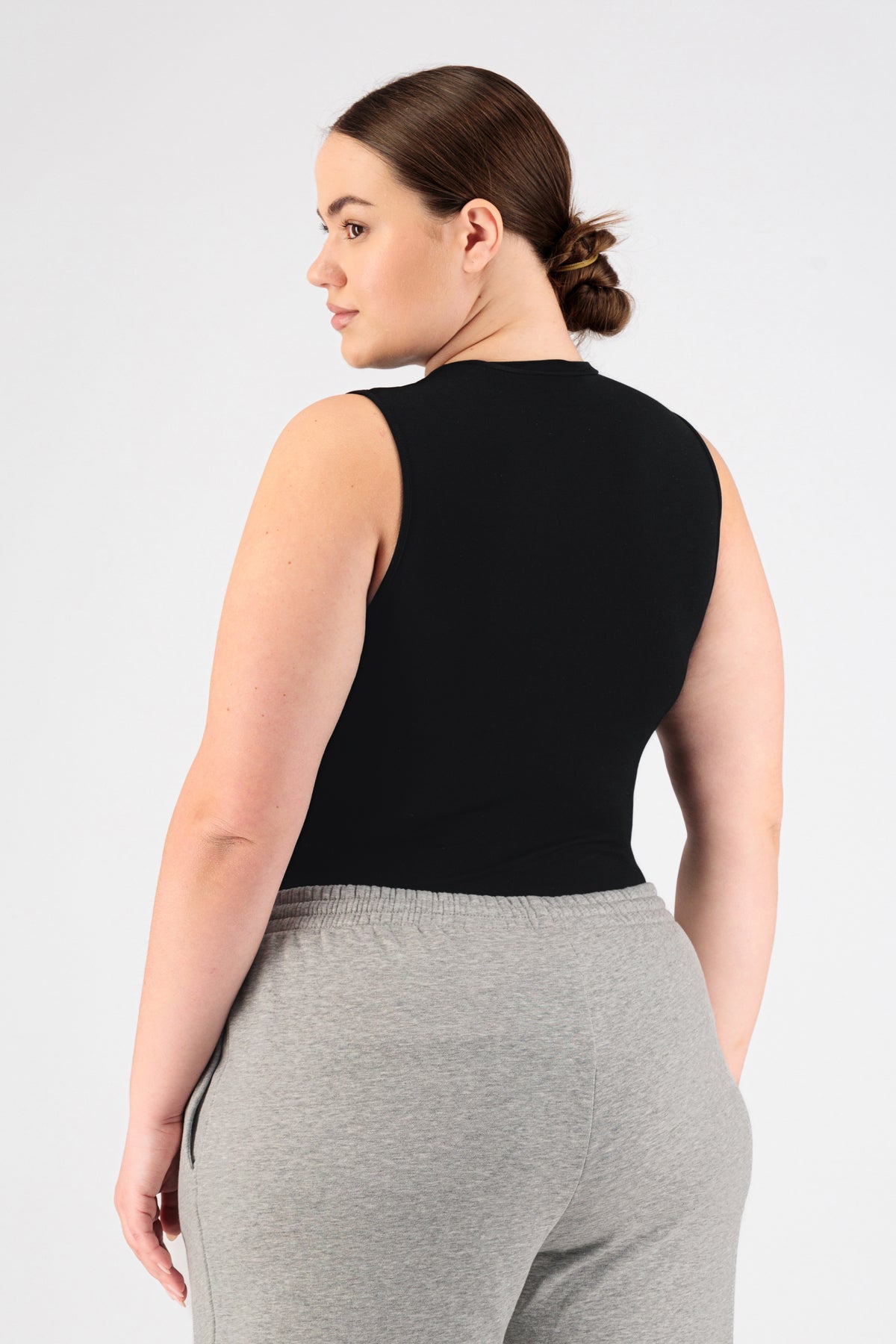 A girl wearing FARES' sleeveless layer is shown from the back while looking over her left shoulder. Colour description: Black.