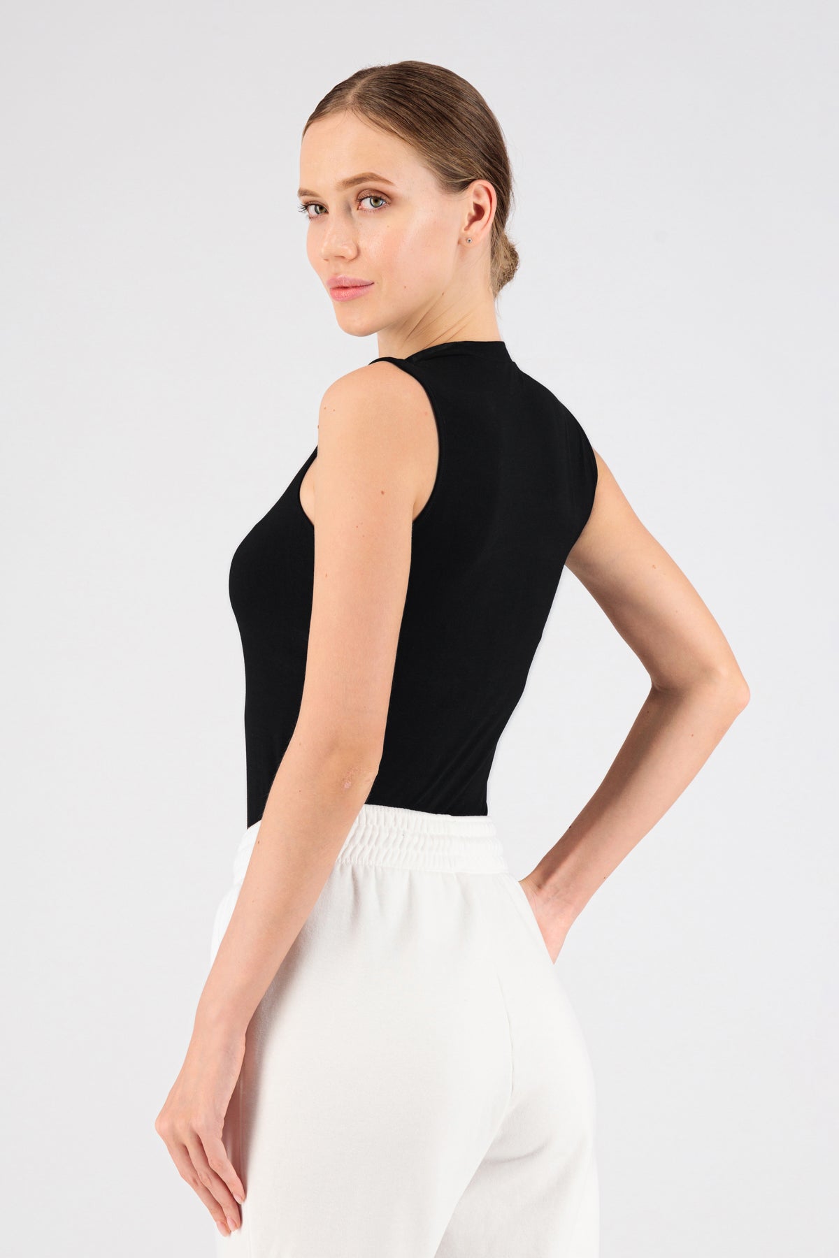 The girl wearing FARES' sleeveless layer is shown from the back. She is looking back over her left shoulder. Colour description: Black.