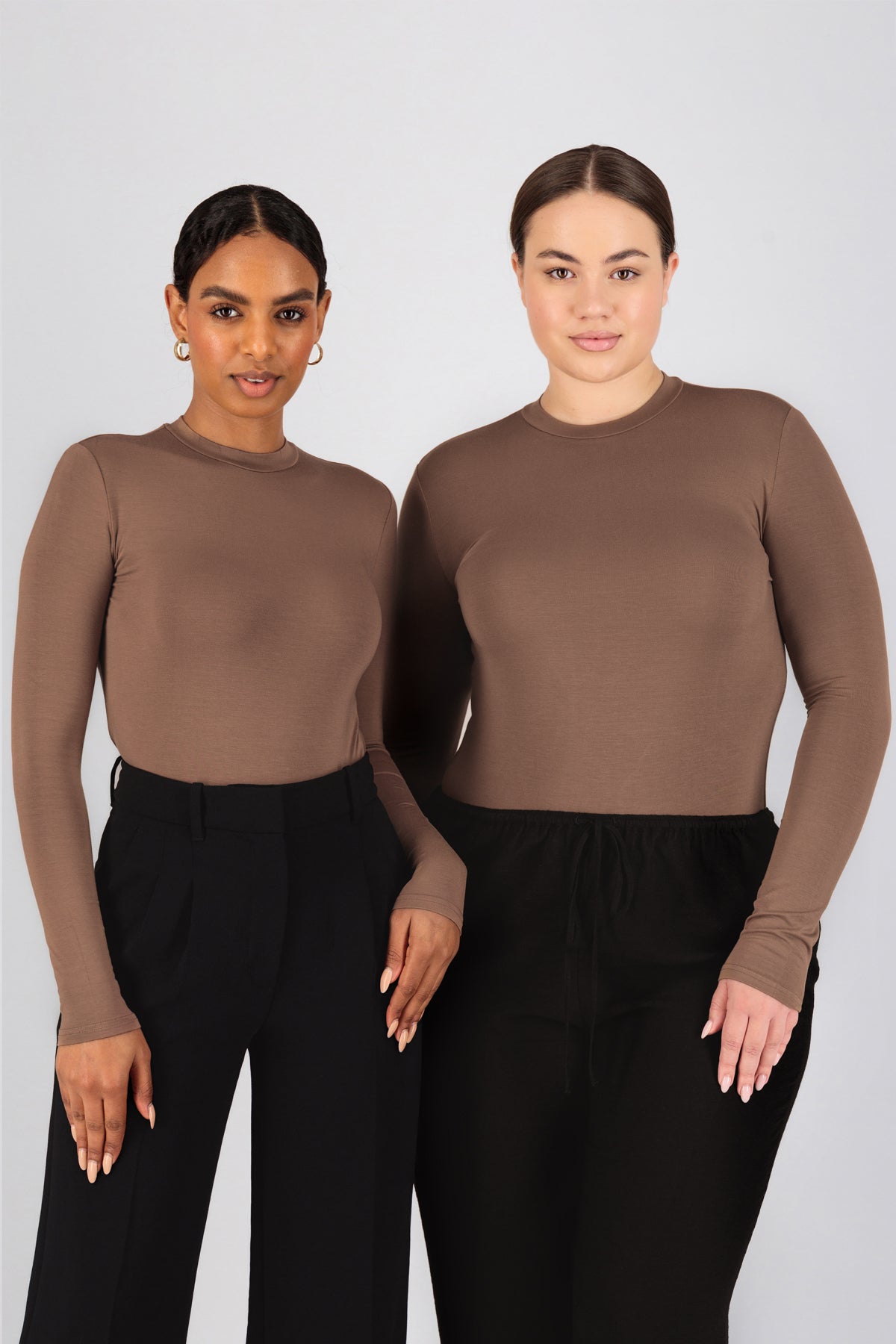 Two girls are standing side by side in FARES' best base layer clothing. Colour description: Bronze.