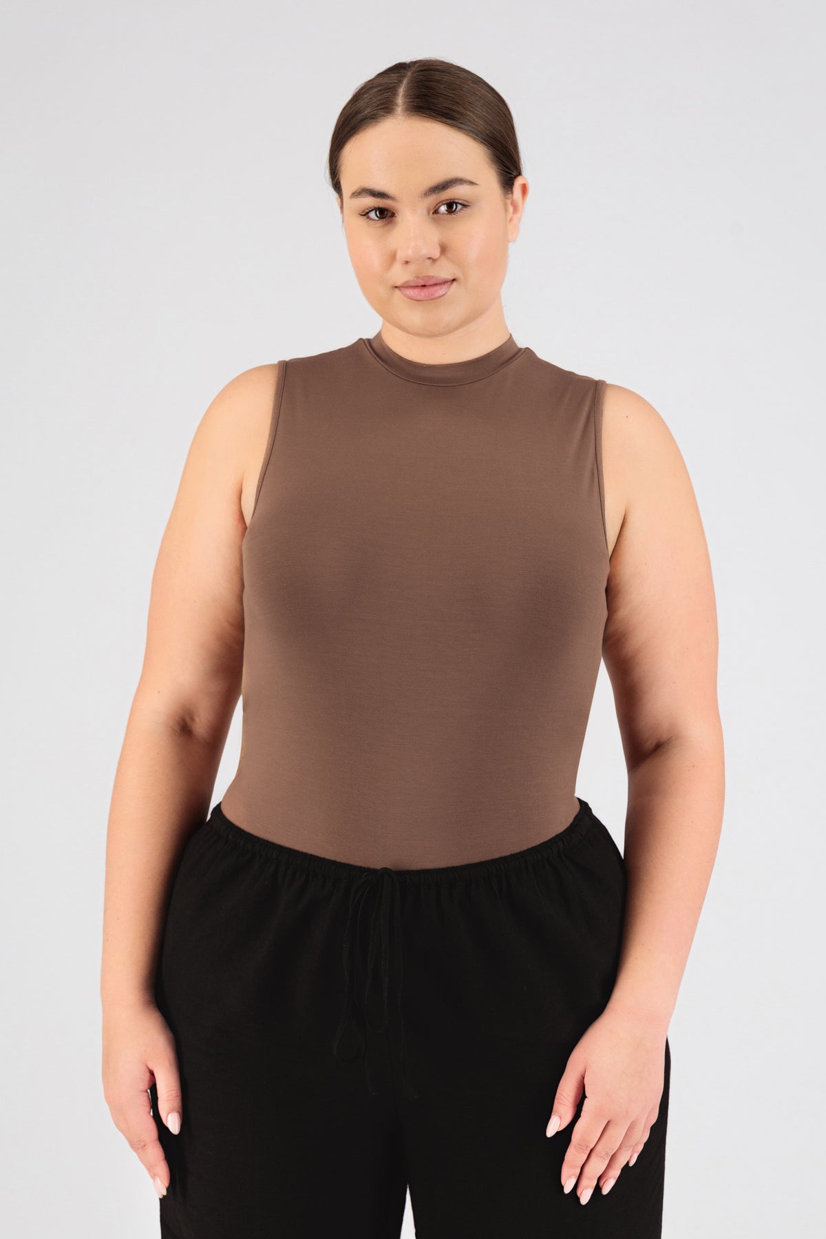 The front of a model standing in FARES' sleeveless layer. Colour description: Bronze.