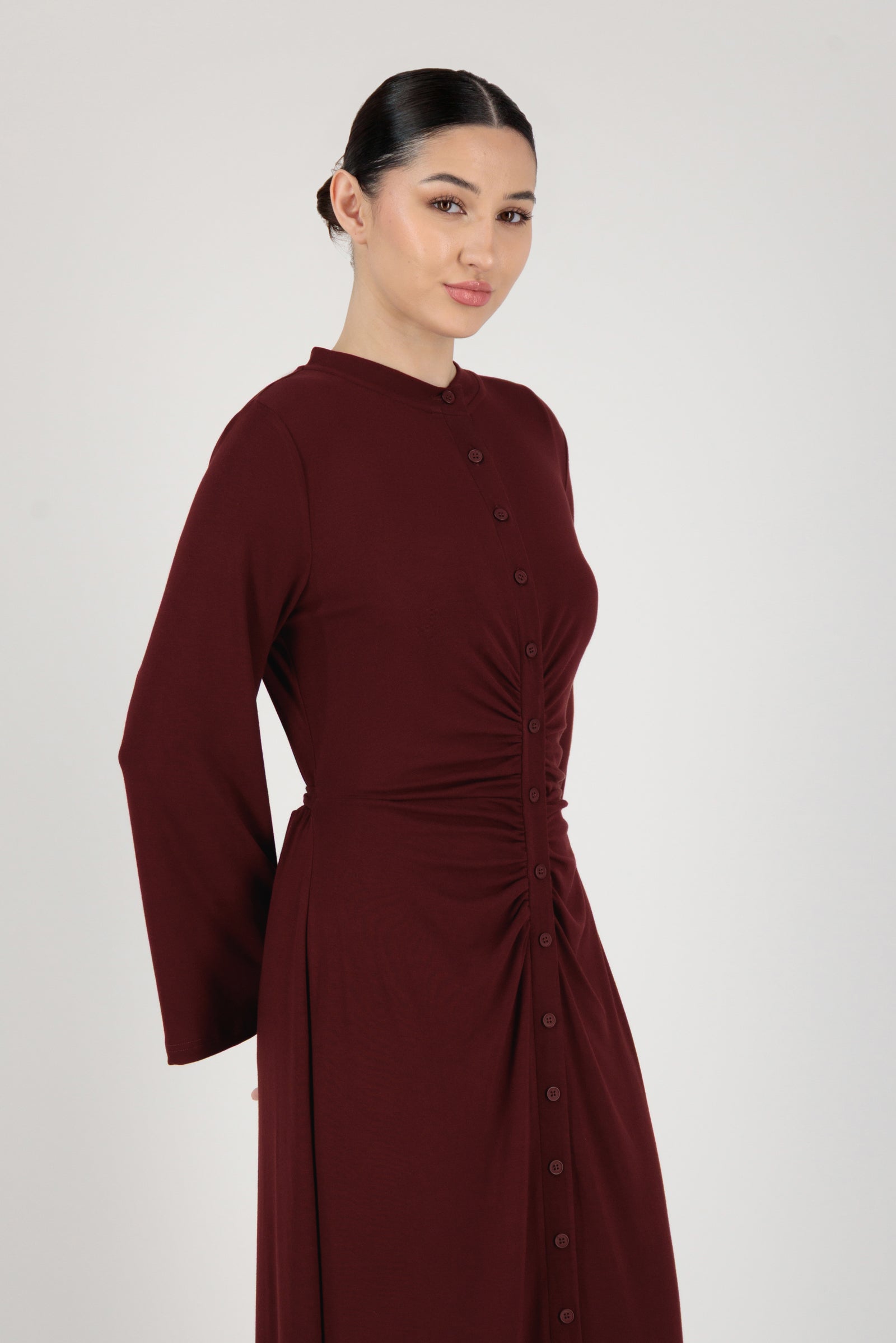 Side angle of the FARES Gathered Waist Knit Dress in Black Cherry presenting a refined knit dress shape with gentle structure.