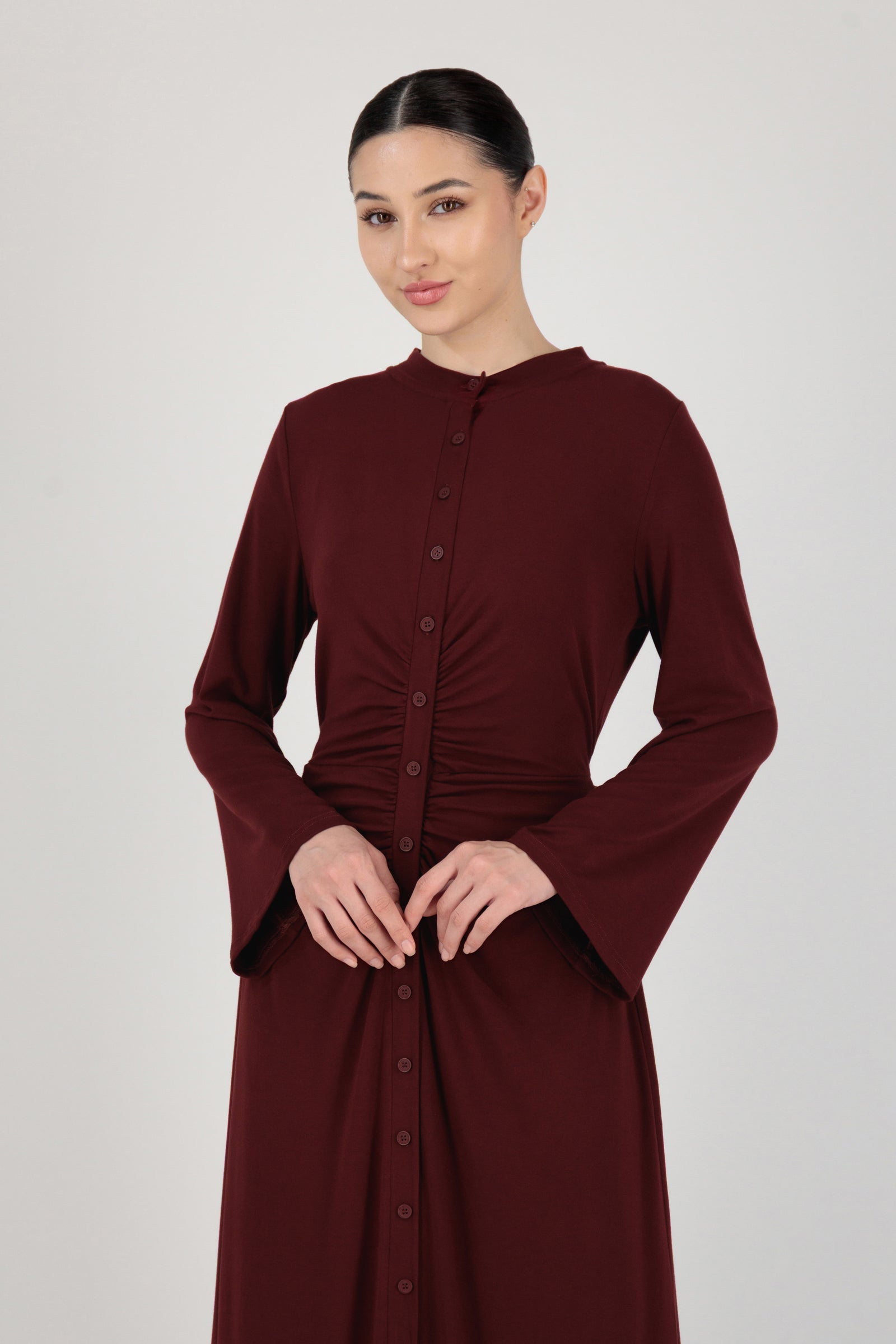 Front view of the FARES Gathered Waist Knit Dress in Black Cherry styled naturally, showing how the gathered waist defines the long sleeve dress.