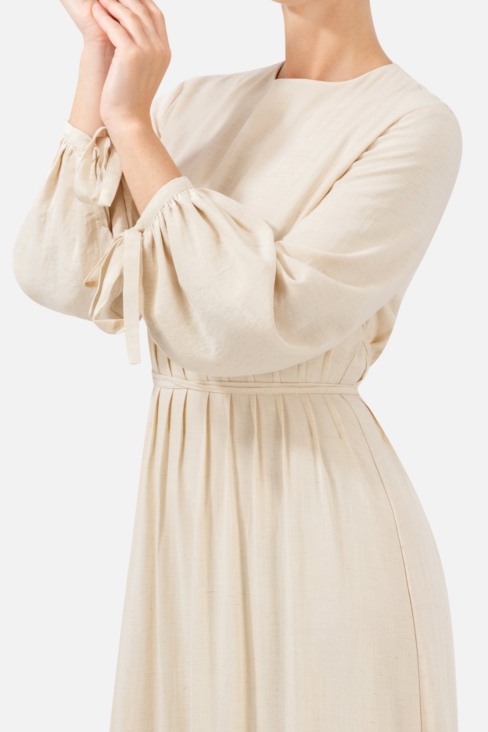 Close-up of the tie waist and gathered sleeve detail on the Crema dress.