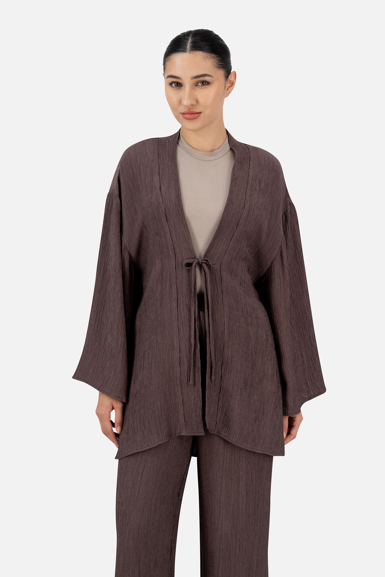 Woman wearing the Icy Brown bow cardigan over a neutral top, front view with a relaxed silhouette.