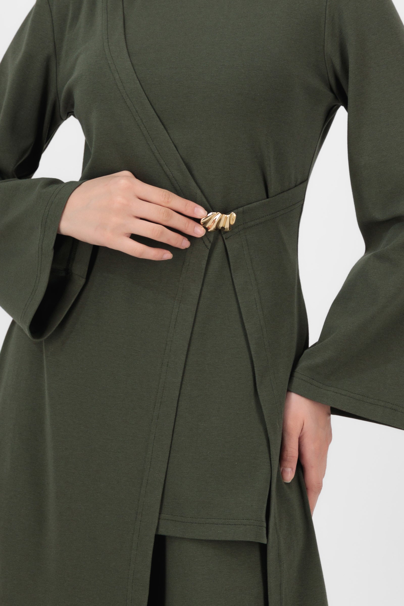 Close-up of the Gold Accent Wrap Top in Evergreen showing the textured fabric, gold hardware, and wrap construction that give this long sleeve wrap top its elevated, luxe feel.