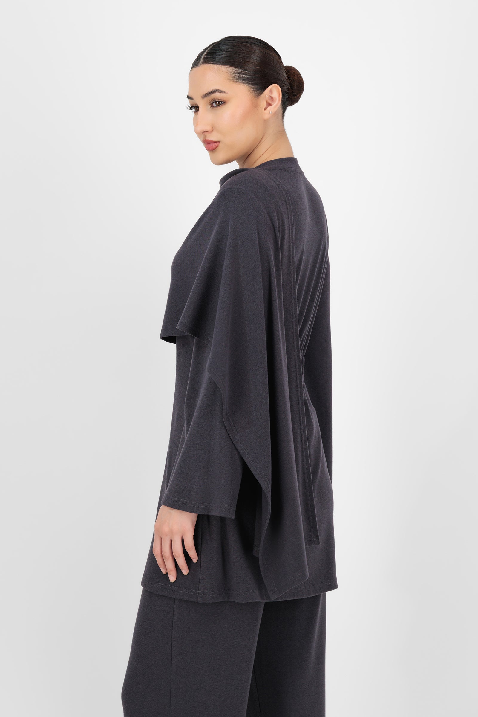 Side angle of the Draped Shawl Knit Top Charcoal capturing the cozy texture and draped neckline that add a polished feel to simple tops for women.