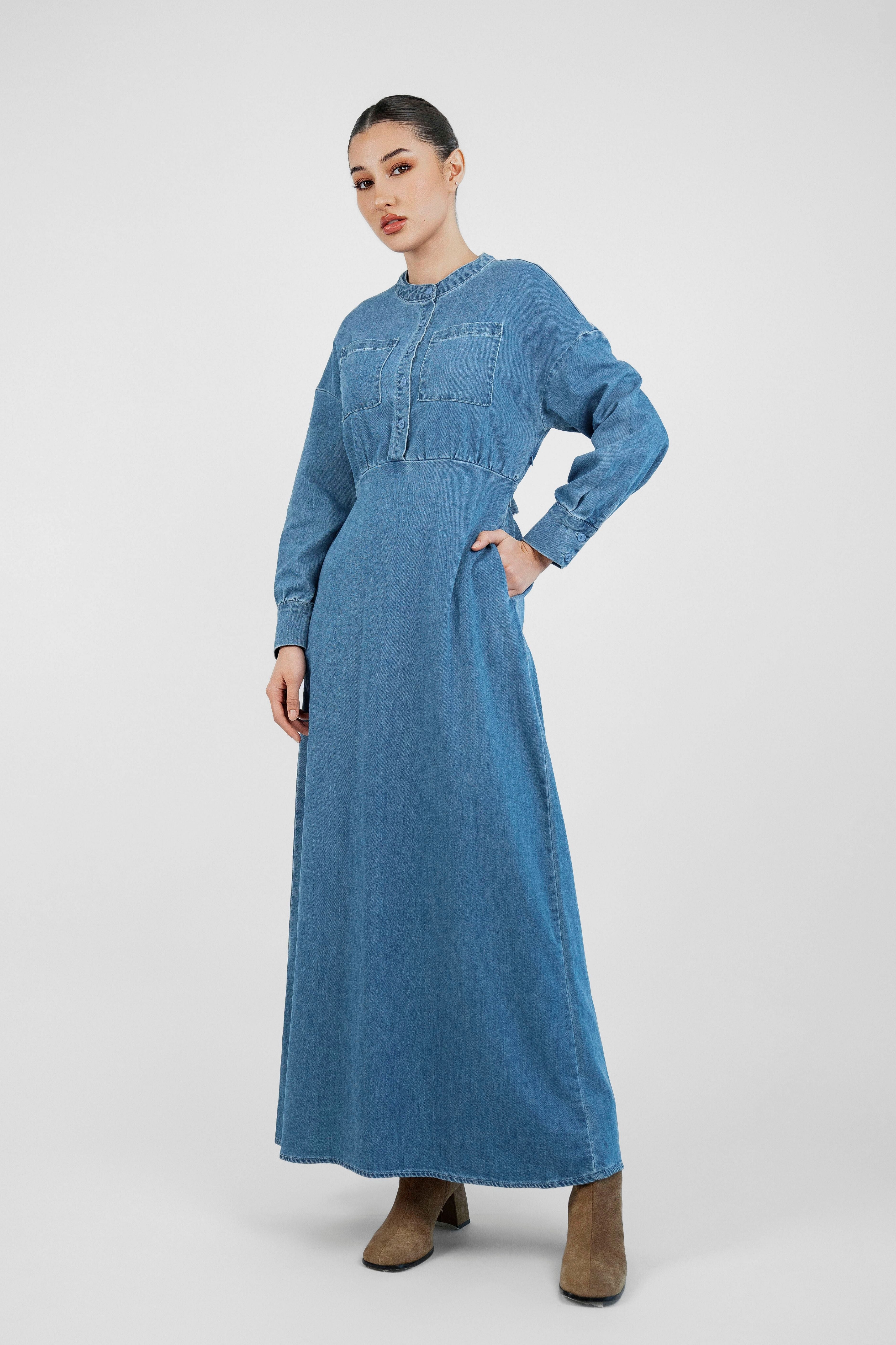 A model is wearing FARES' denim dress while facing the camera and her hands are in her pocket. Colour description: Blue.
