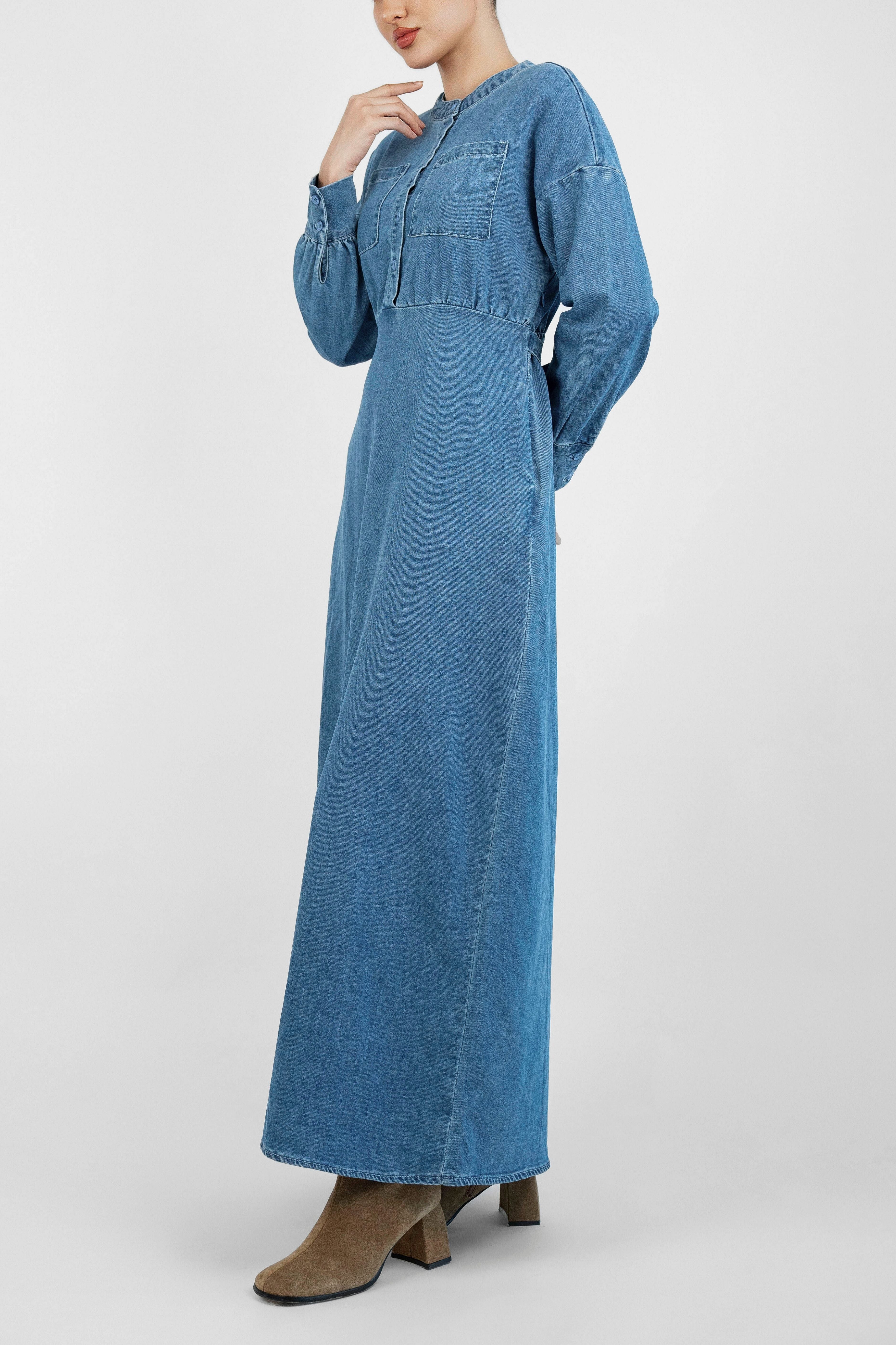 A model is wearing FARES' denim dress while touching her neck. Colour description: Blue.