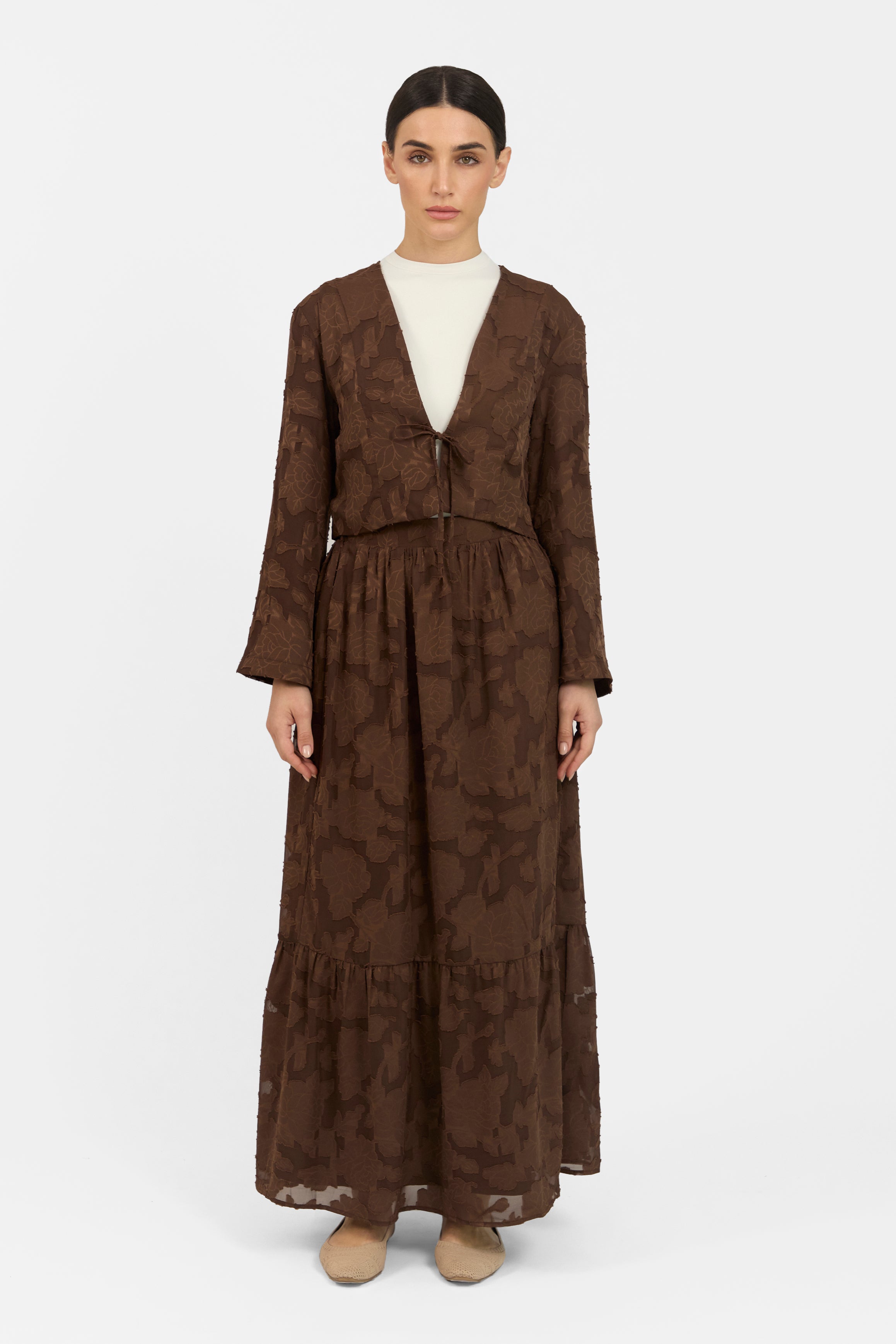 A gir is posing in a Floral Cut Out Cropped Cardigan and Skirt Set.	Colour: Chocolate