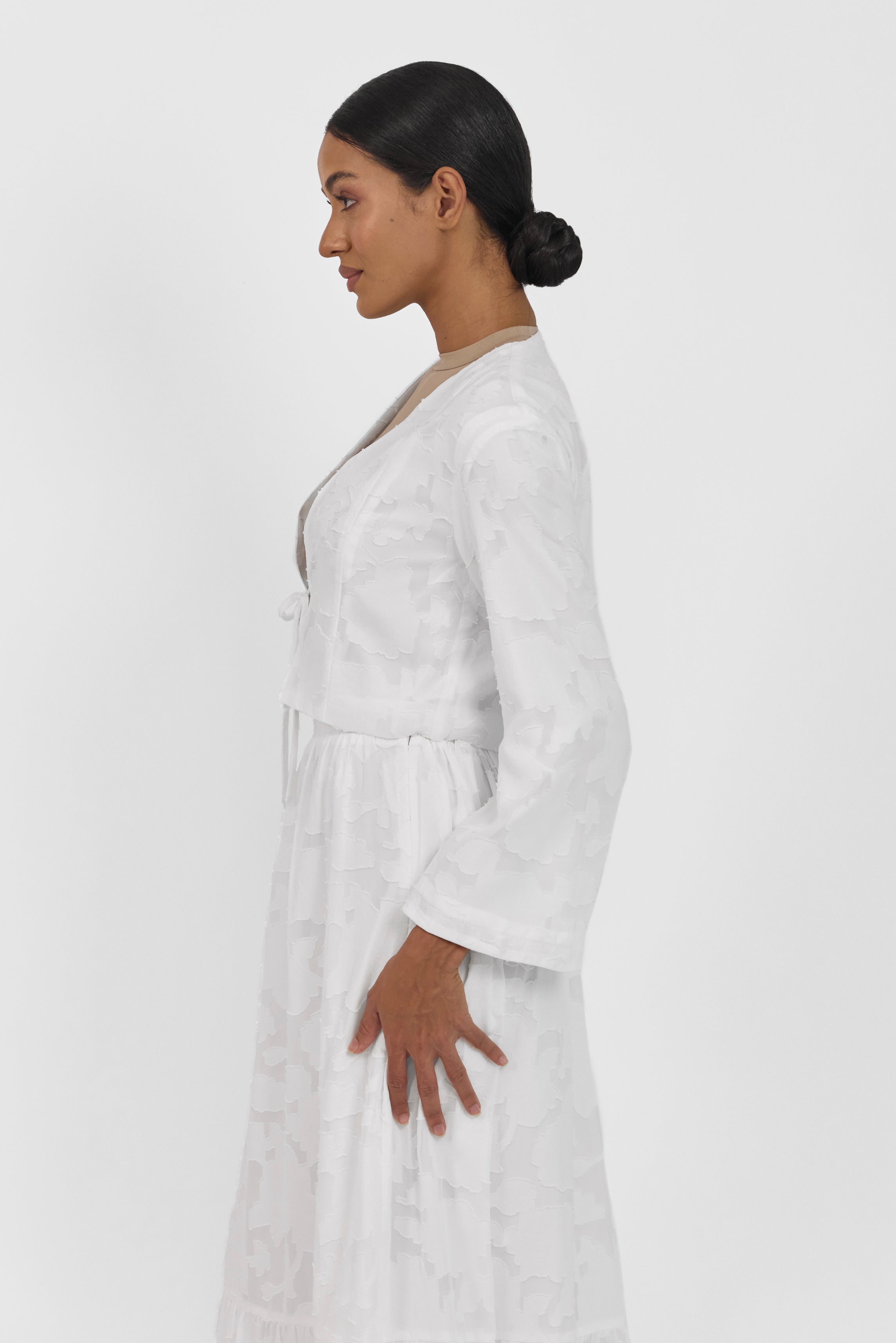 A side pose from a model wearing a Floral Cut Out Cropped Cardigan and Skirt Set . Colour: White