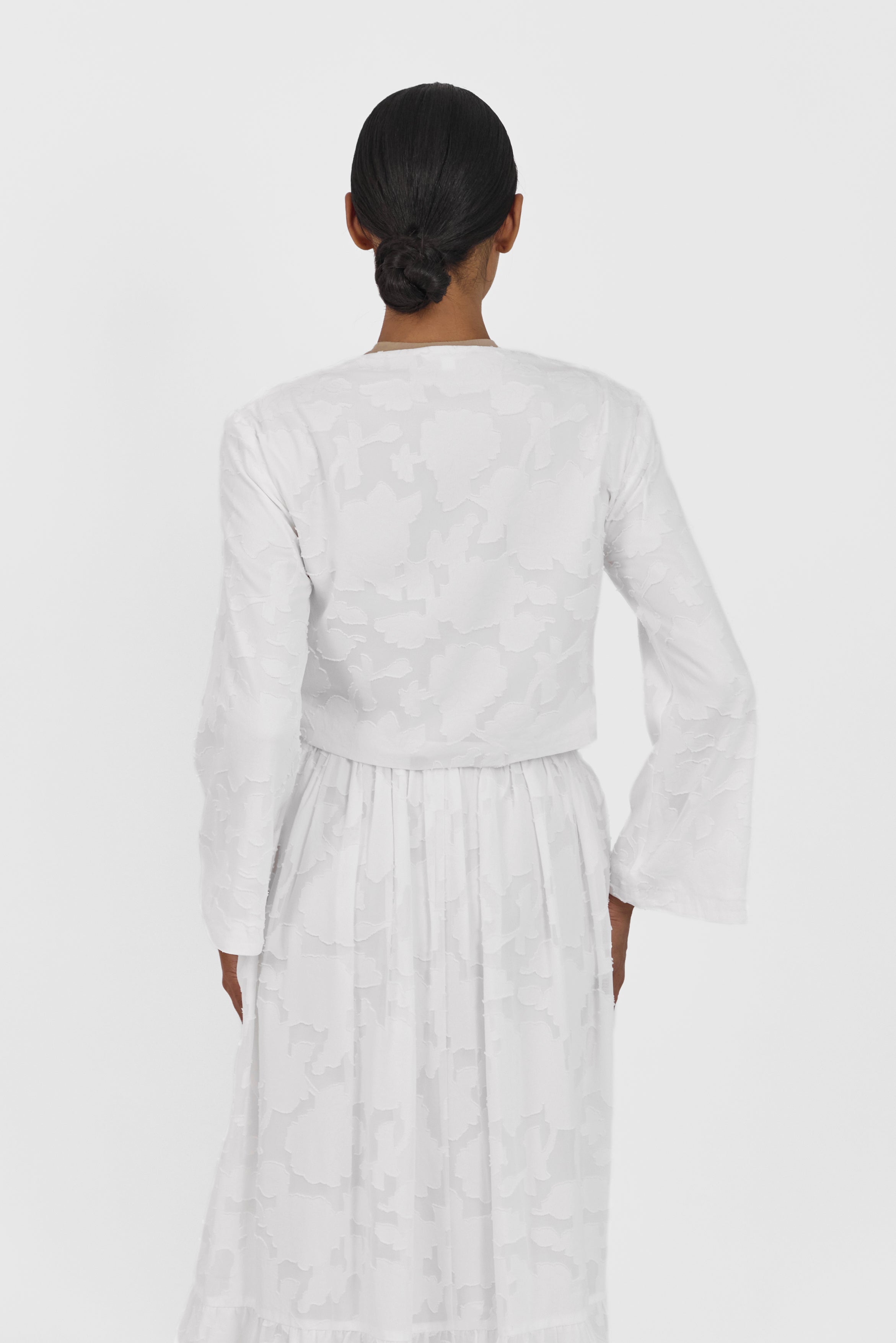 A back pose of a girl wearing a Floral Cut Out Cropped Cardigan and Skirt Set Colour: White