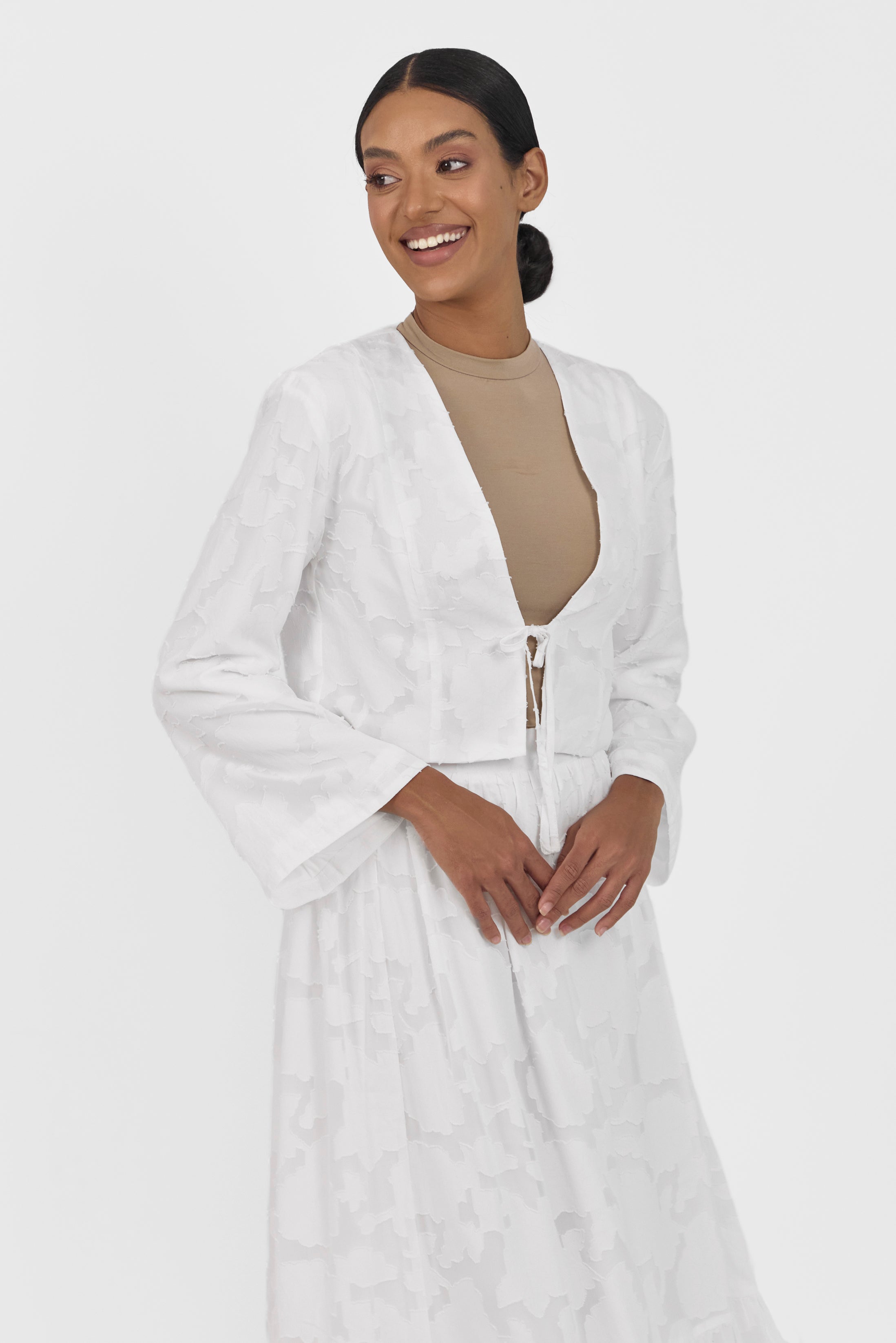 A girl is looking over her shoulder while wearing a Floral Cut Out Cropped Cardigan and Skirt Set Colour: White