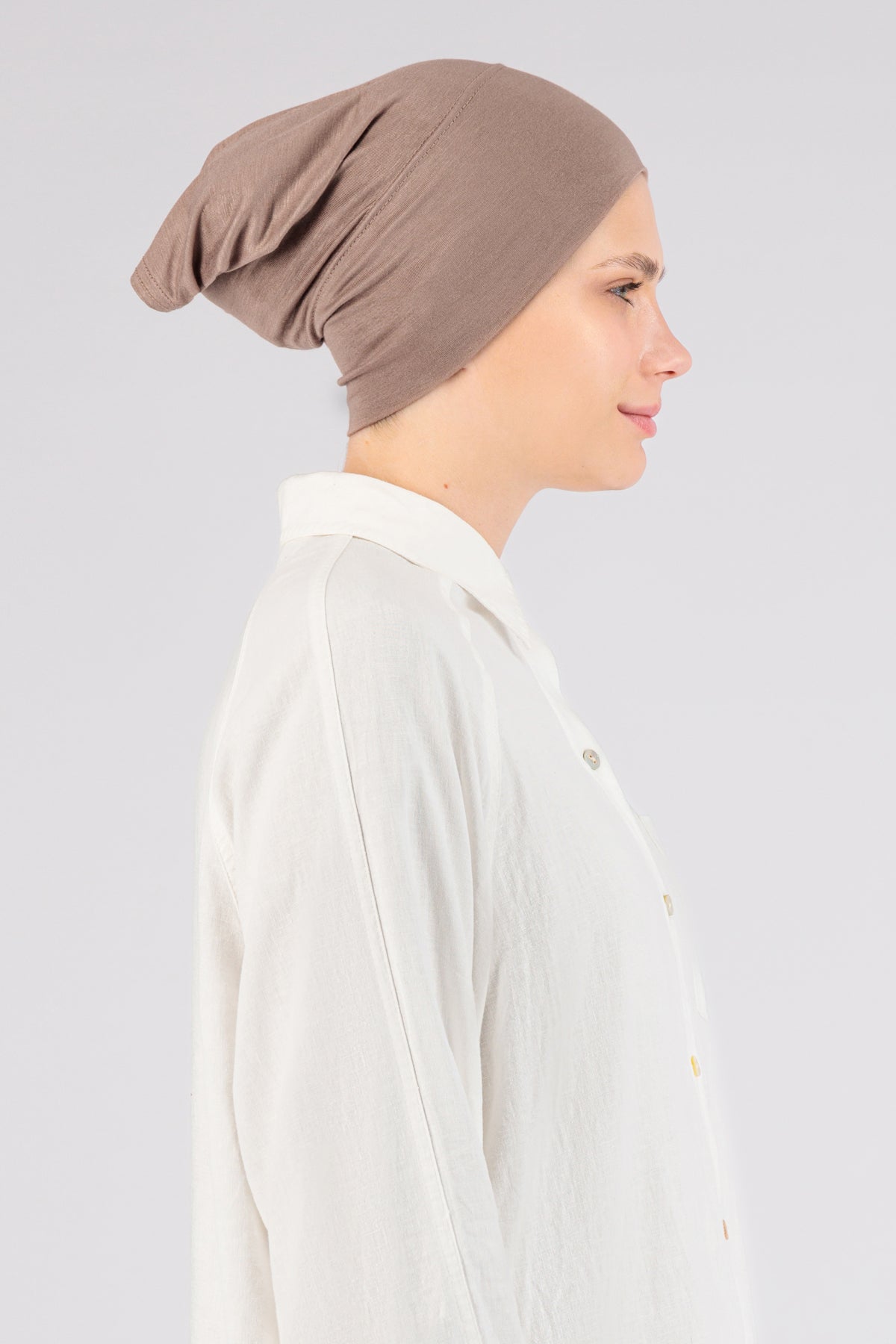 The right profile of a female model wearing a hijab undercap. Colour description: blush pink.