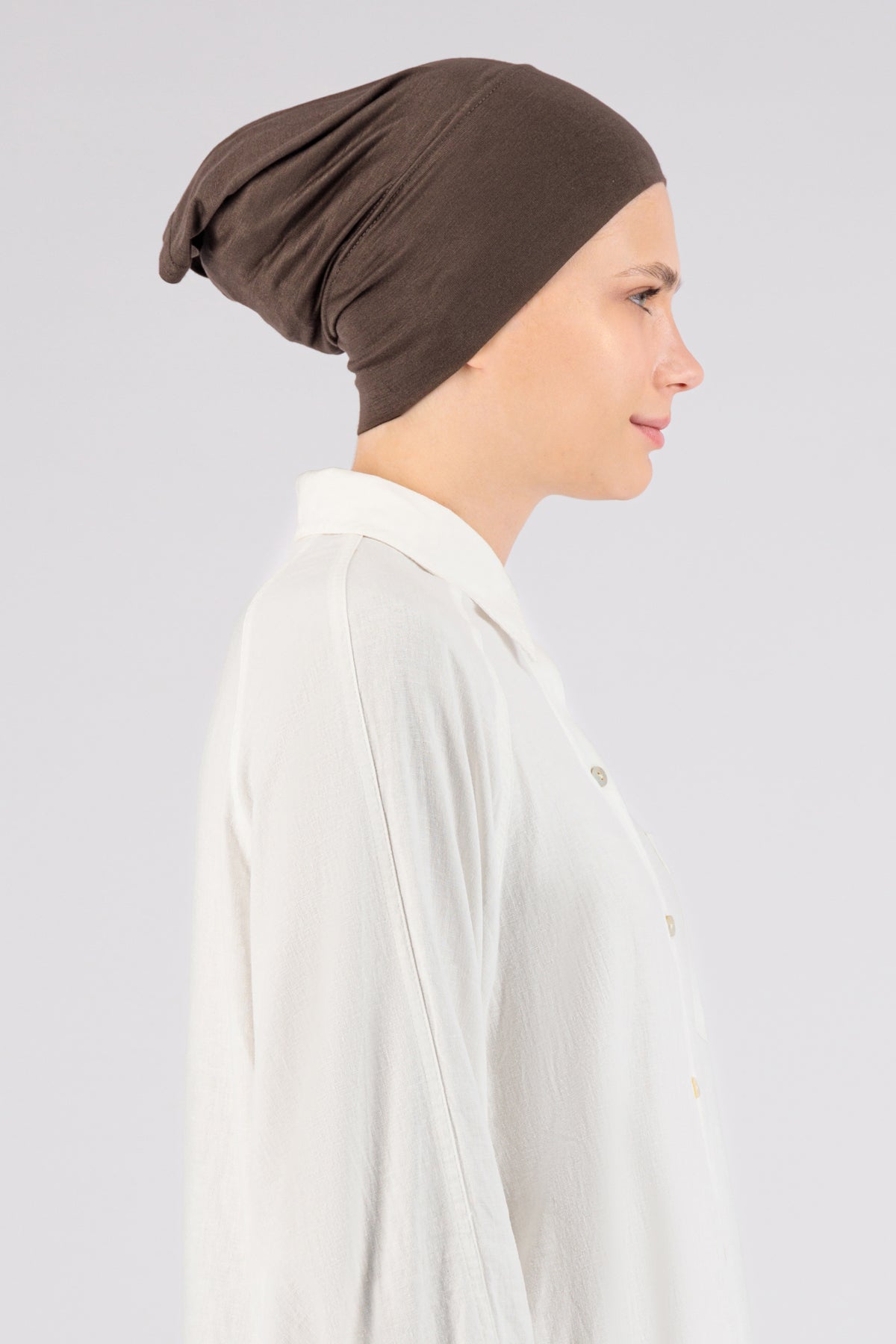 The right profile of a female model wearing a hijab undercap. Colour description: cool dark brown.