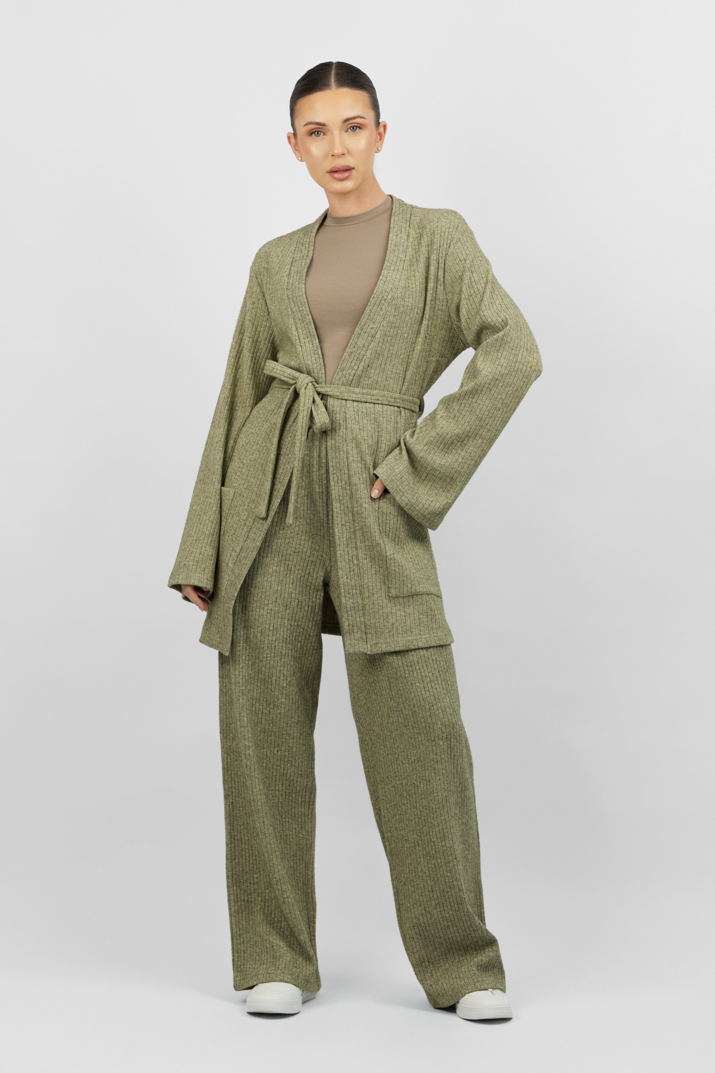 A model is facing the camera wearing FARES' knit belted cardigan. Colour description: Muted Green.
