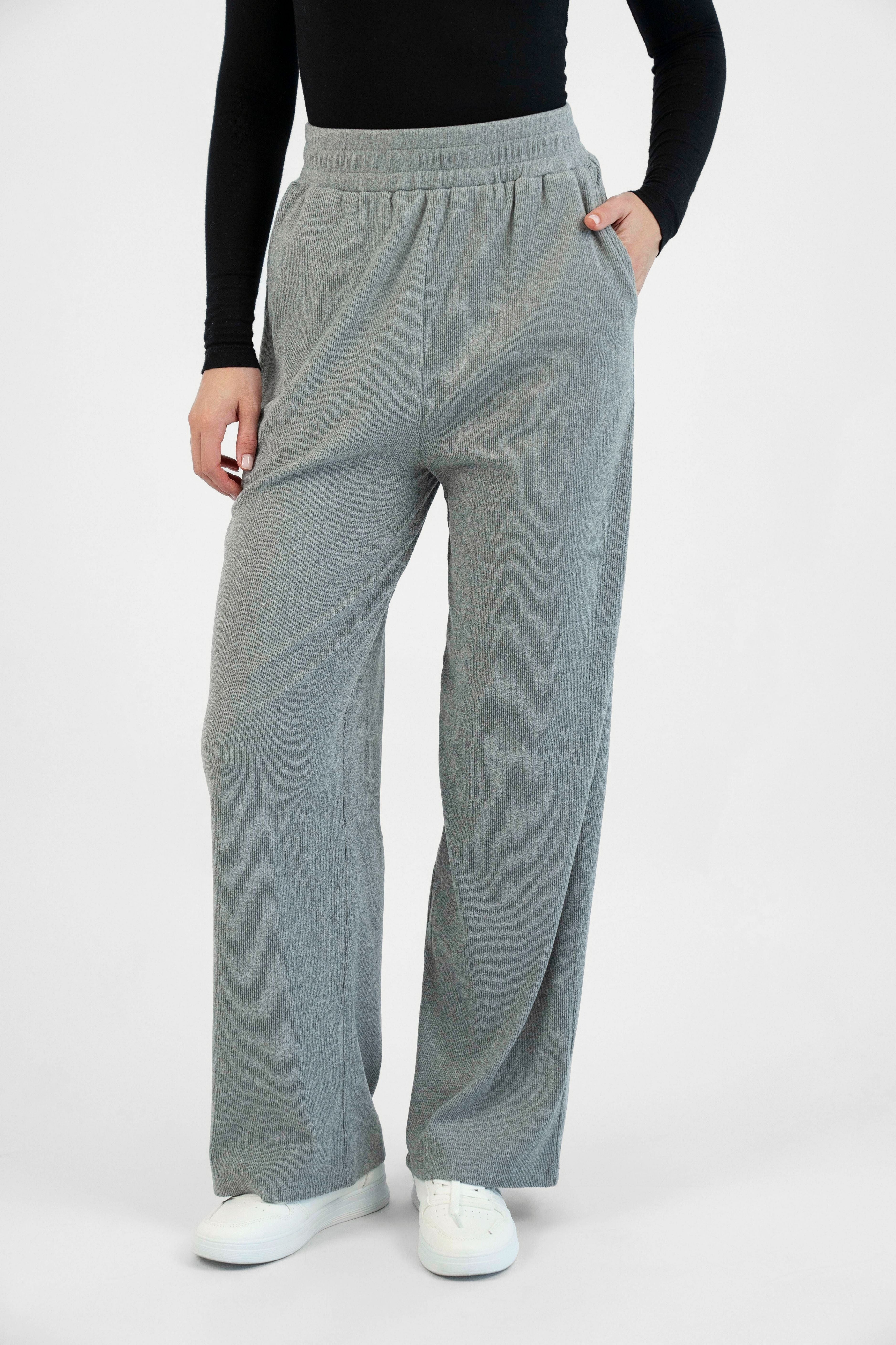 A model is wearing FARES' velour knit pants with her hand in her pocket. Colour description: Heather Grey.
