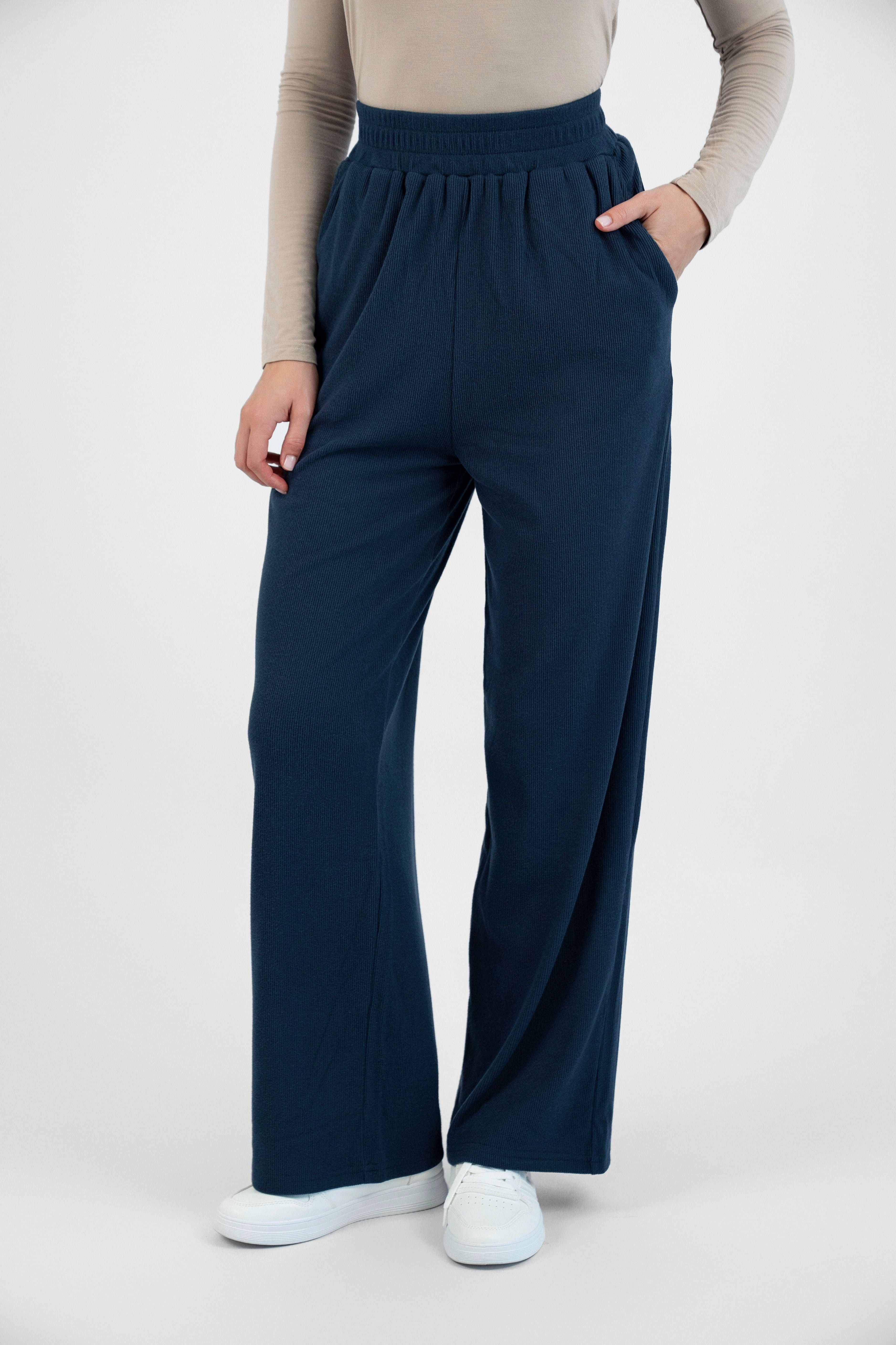 A girl is wearing FARES' velour knit pants with her hand in her pocket. Colour description: Navy Blue.