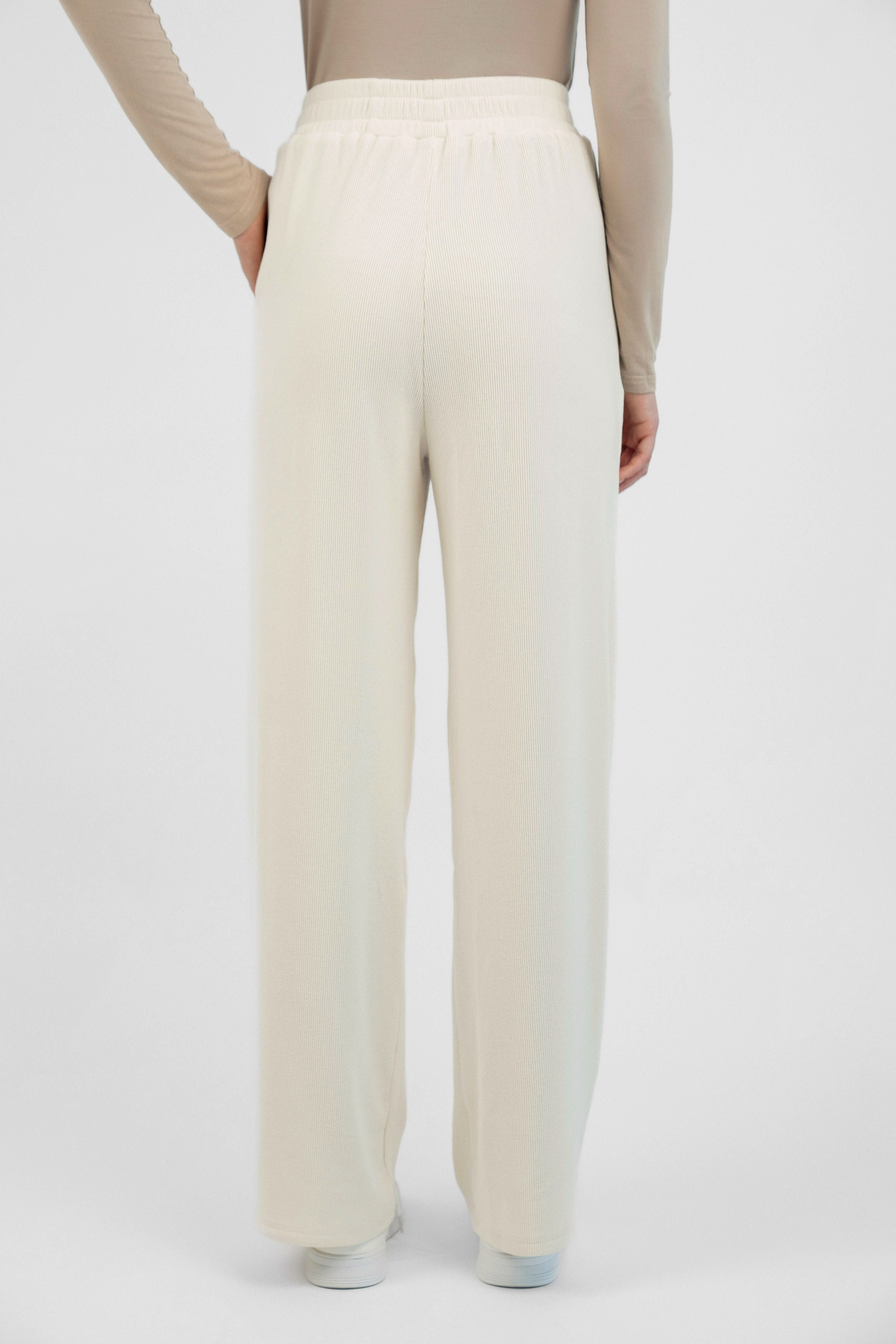 Colour description: Creamy Page. FARES' velour pants are shown fromthe back.