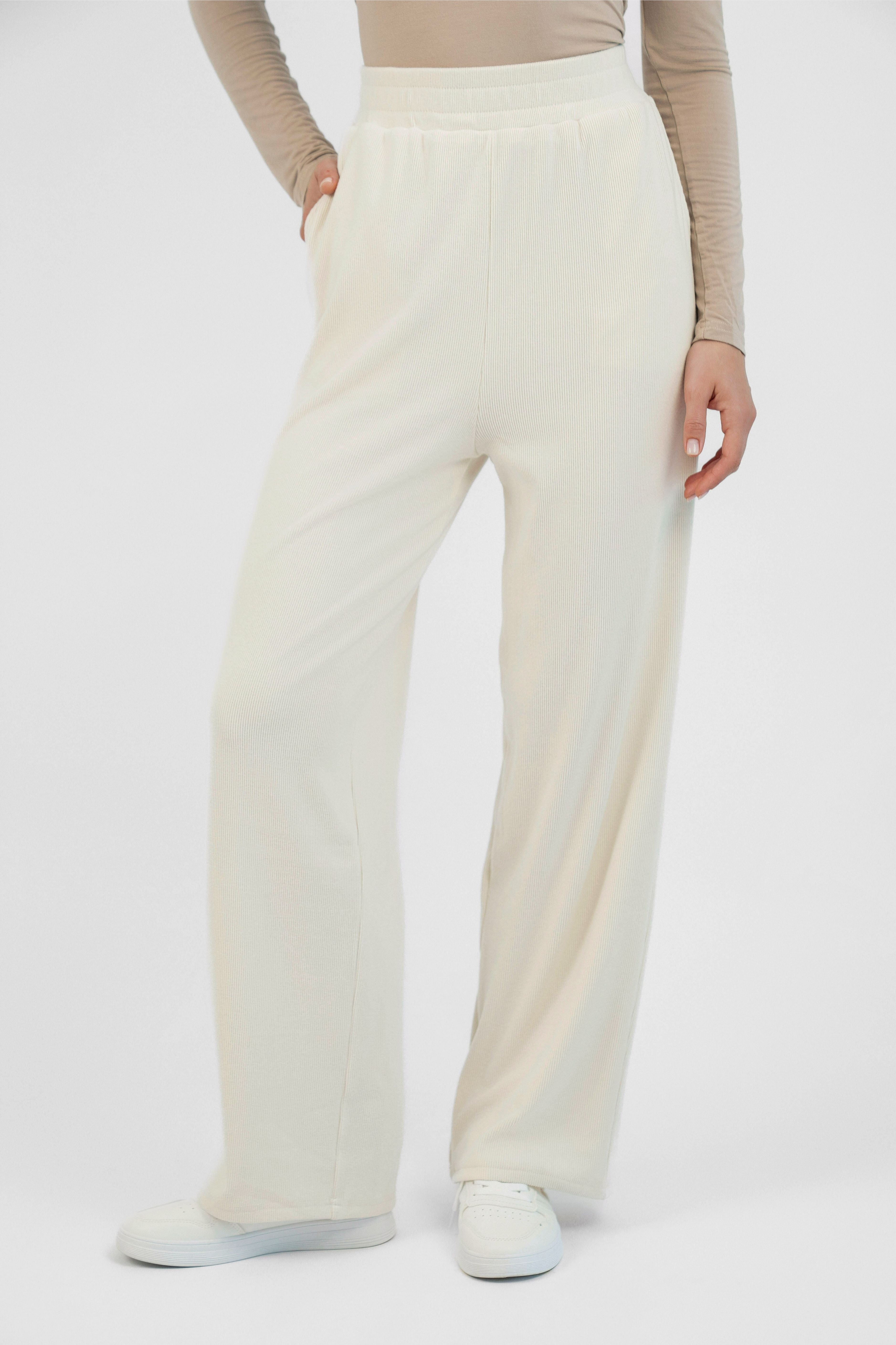 A girl is wearing FARES' velour knit pants with her hand in her pocket. Colour description: Creamy Page.