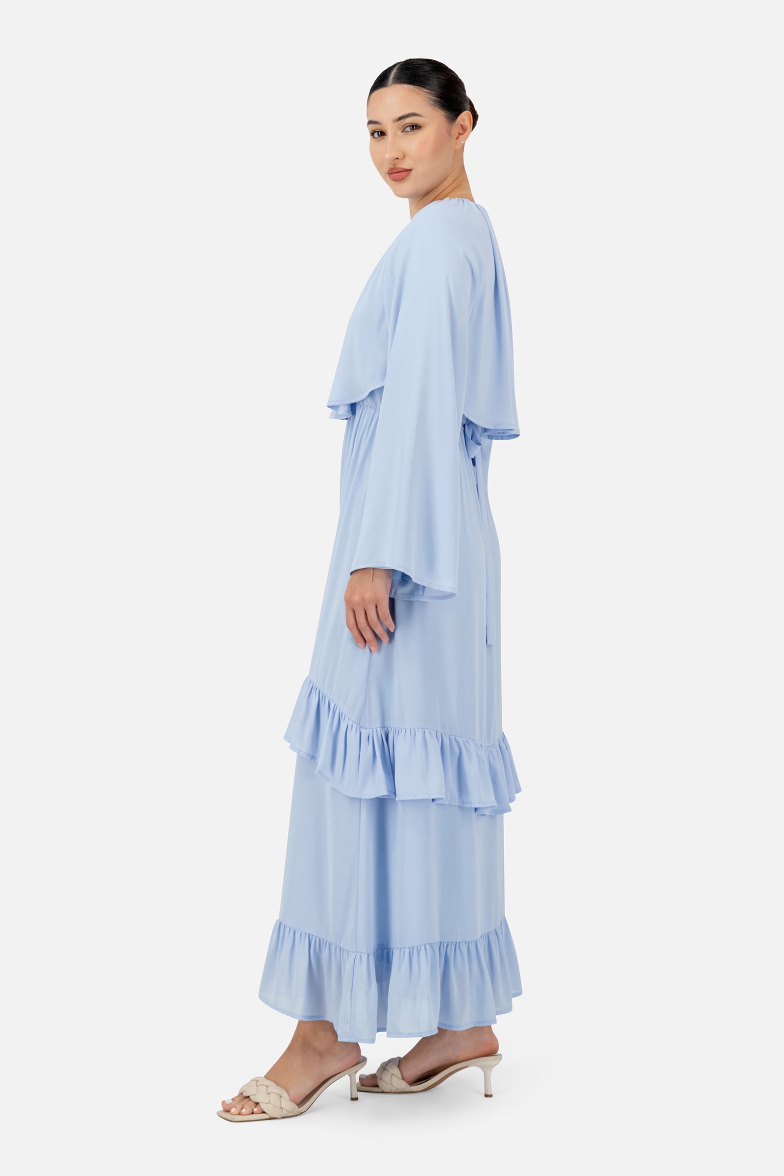 Side profile of the FARES Chiffon Layer Dress in Powder Blue highlighting the airy drape and tiered hem of the maxi dress.