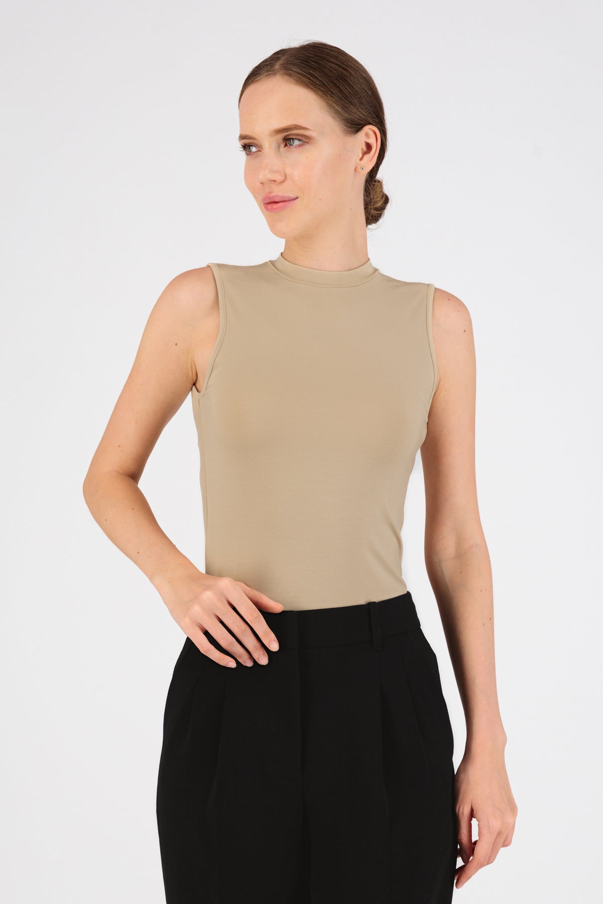 The front of a model standing in FARES' sleeveless layer. Colour description: Buff.