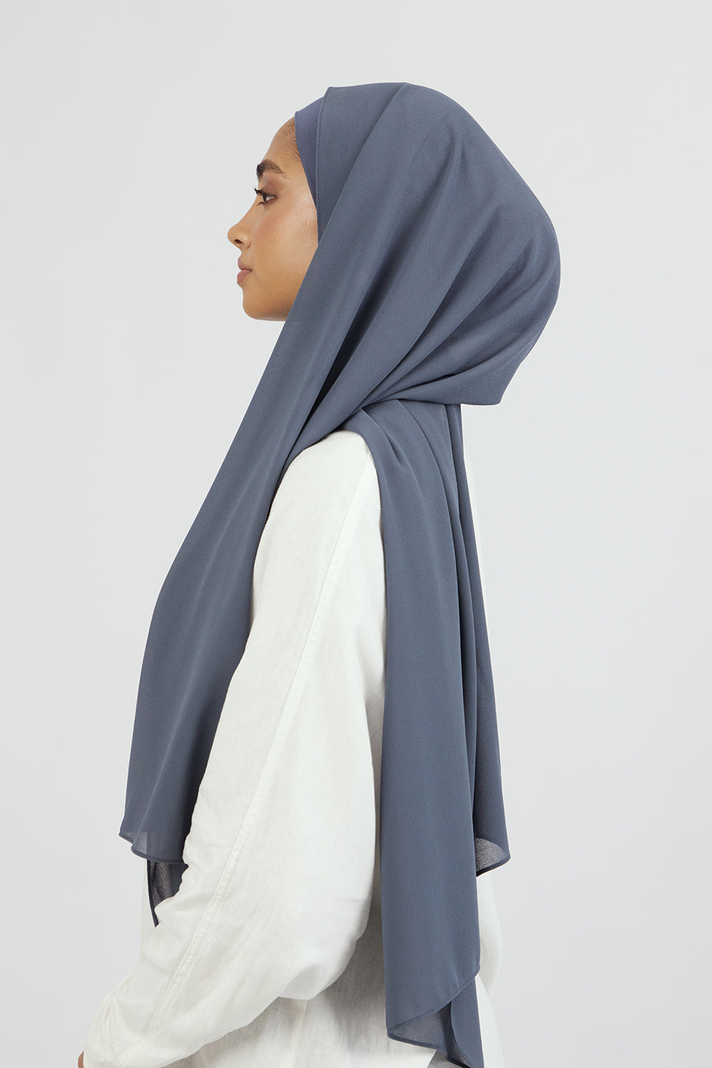 A female model wearing a matching chiffon hijab set. The model is turned to the left. Colour description: denim blue.