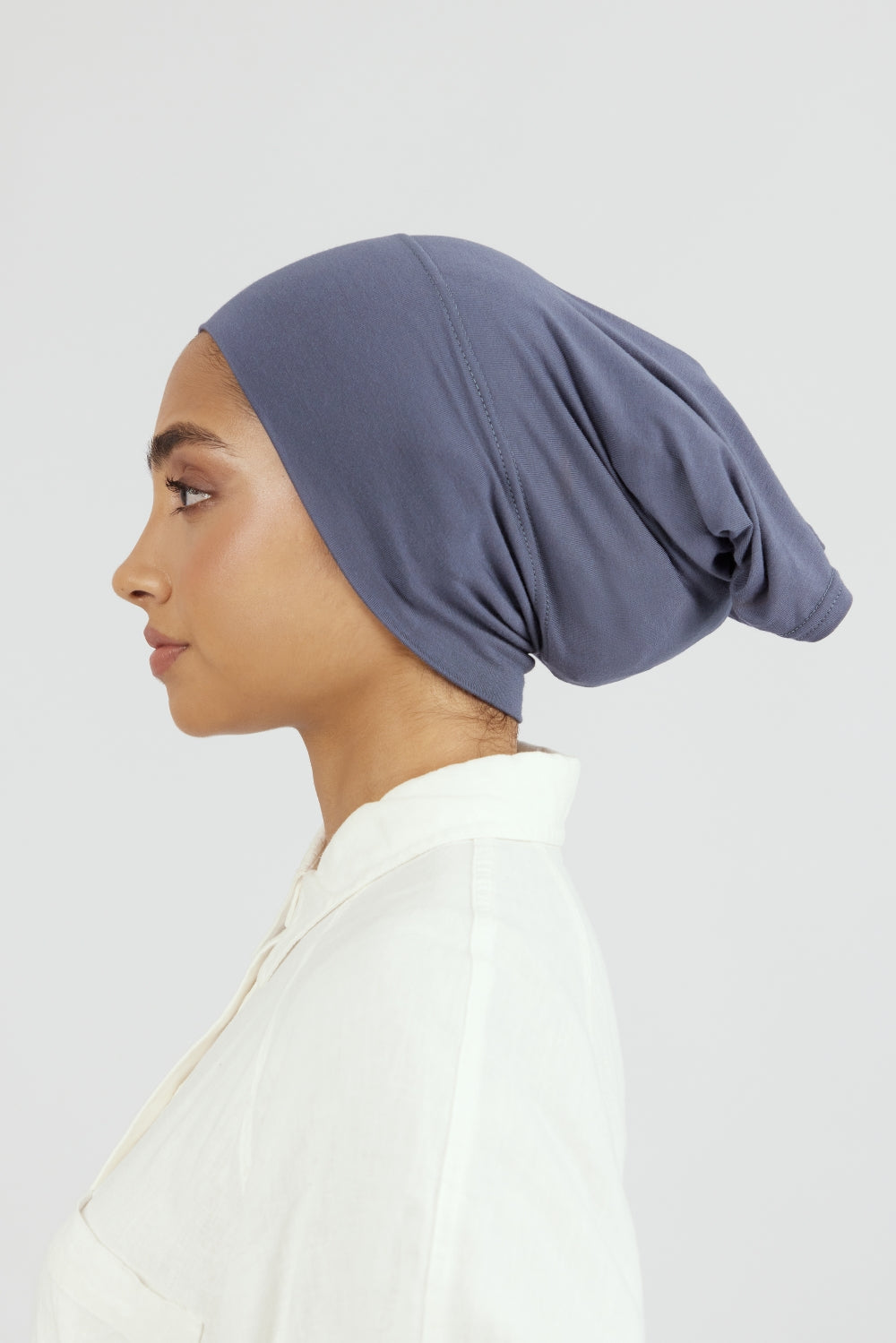 The left profile of a female model wearing a breathable hijab undercap. Colour description: denim blue.