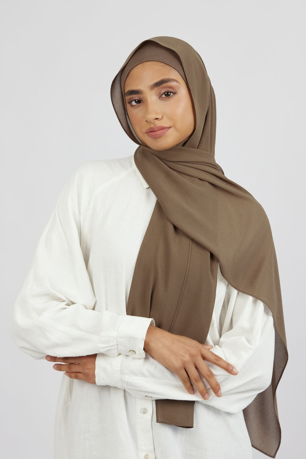 The front of a female model wearing a matching chiffon hijab set. Colour description: medium beige-brown. This hijab fashion wear includes a high quality chiffon hijab and a breathable matching modal jersey undercap.