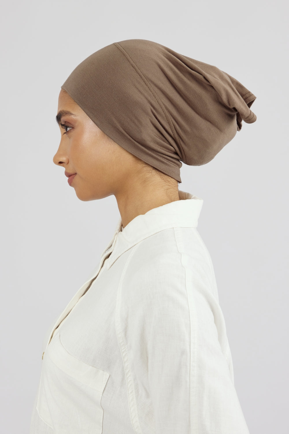 The left profile of a female model wearing a breathable hijab undercap. Colour description: medium beige-brown.