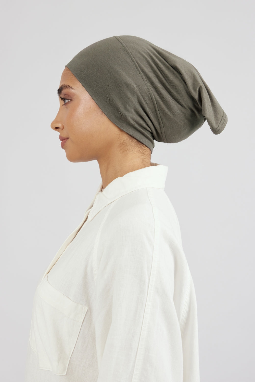 The left profile of a woman wearing a breathable hijab undercap. Colour description: muted green.