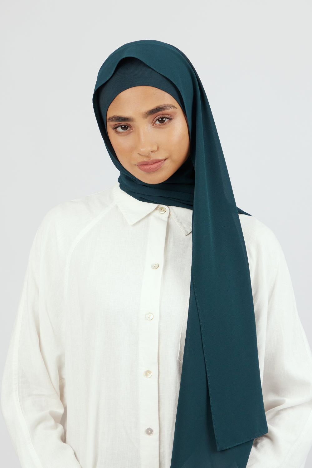 A woman wearing a matching chiffon hijab set. Colour description: dark teal.