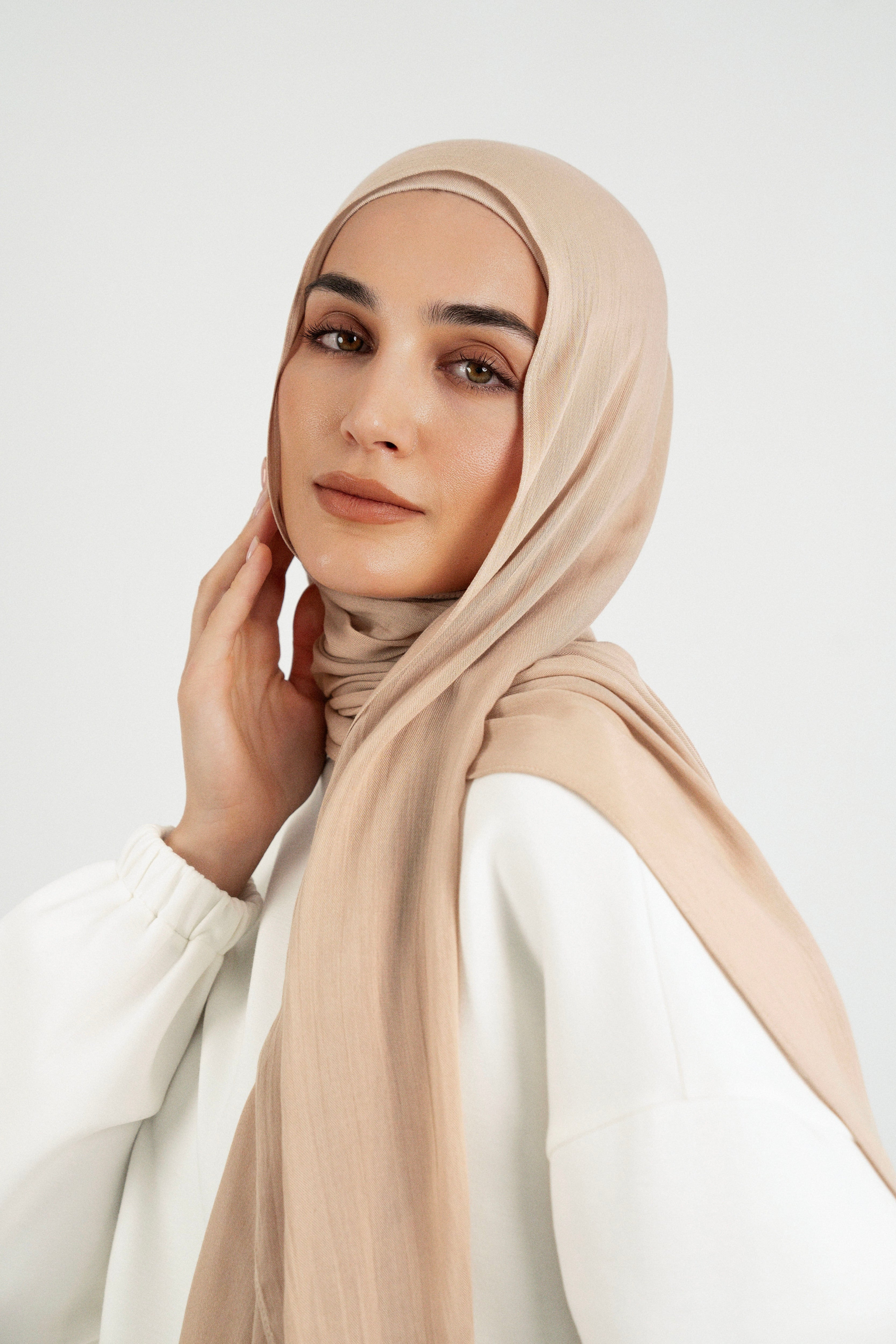 Colour: Biscuit. A close up of girl wearing a Matching Butter Modal Hijab Set and touching her face.