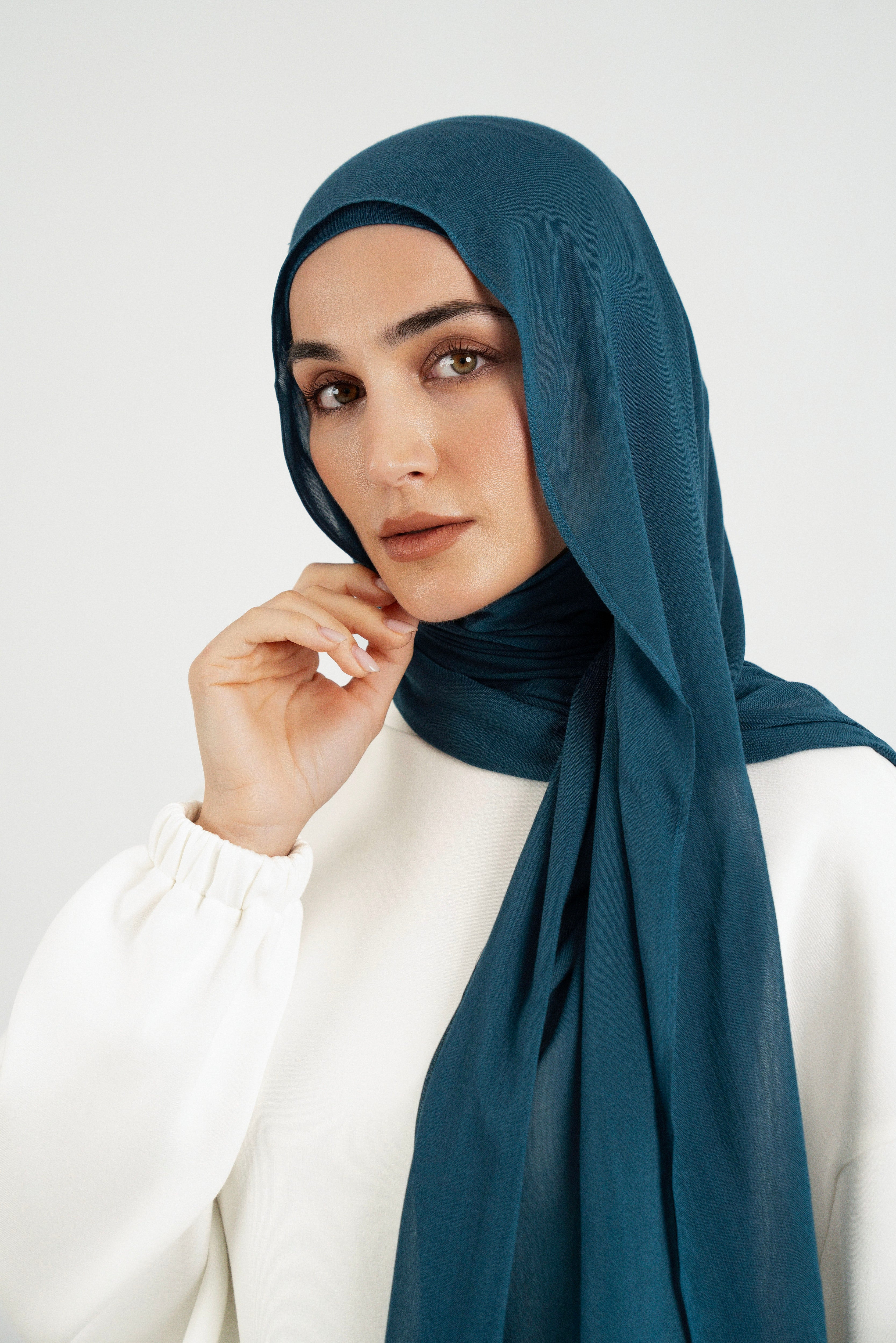 Colour: Real Teal. A close up of girl wearing a Matching Butter Modal Hijab Set and touching her face.