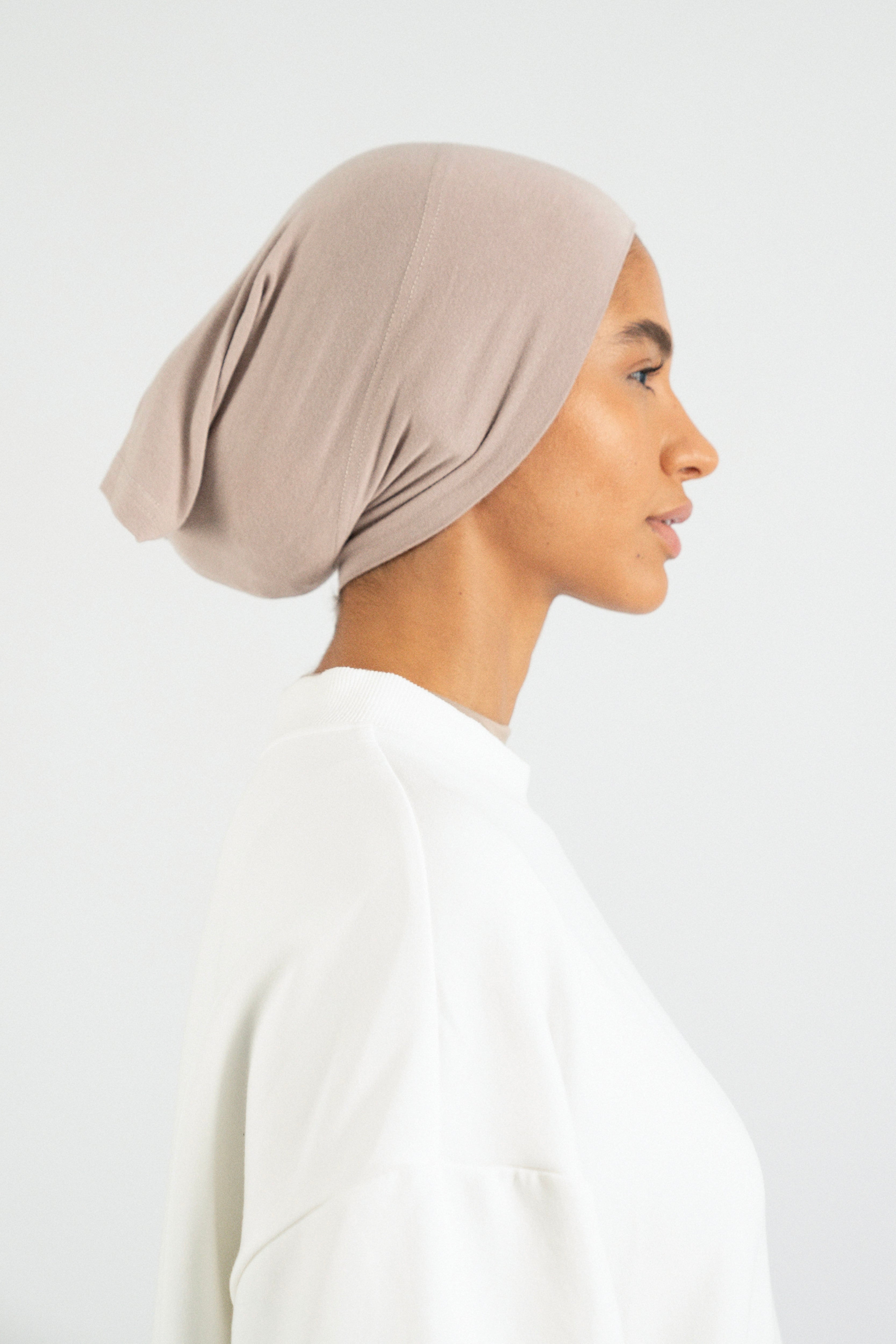 The right profile of a girl wearing a modal hijab undercap. Colour: Sesame.